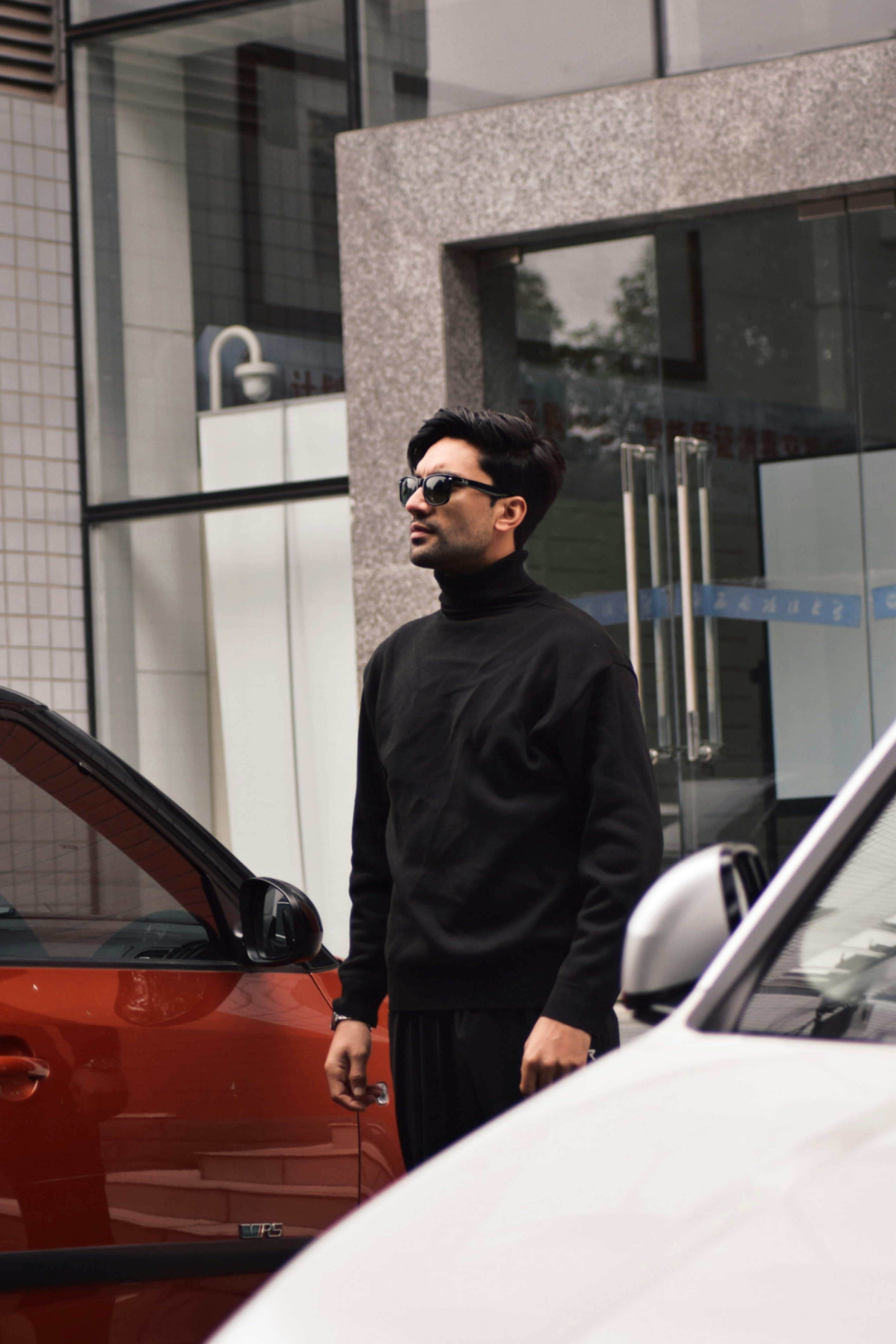 A man standing in front of a red car