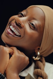 A woman with a headscarf smiling and wearing a white shirt