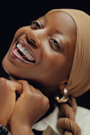 A woman with a headscarf smiling and wearing a white shirt