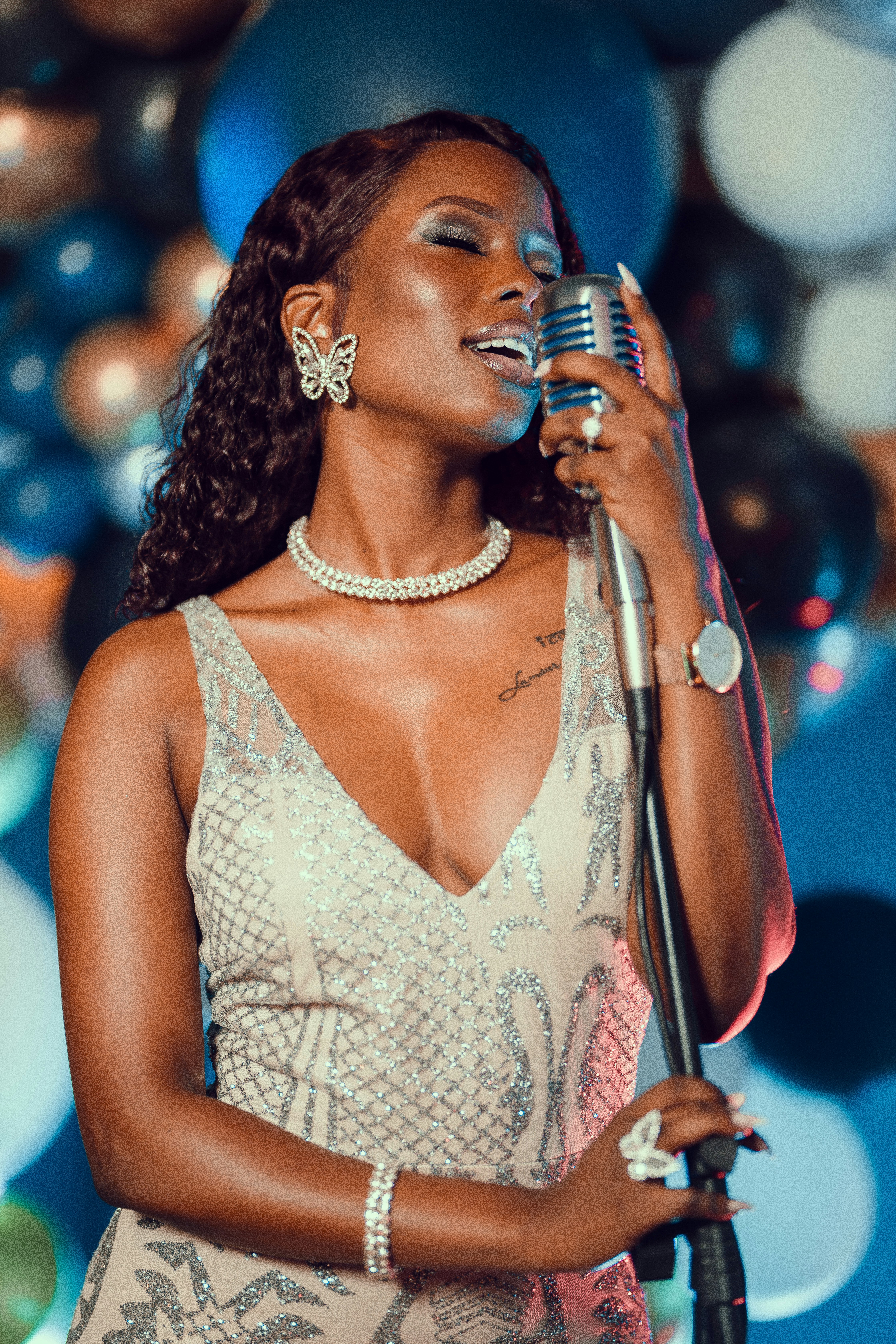 A woman singing into a microphone in front of balloons