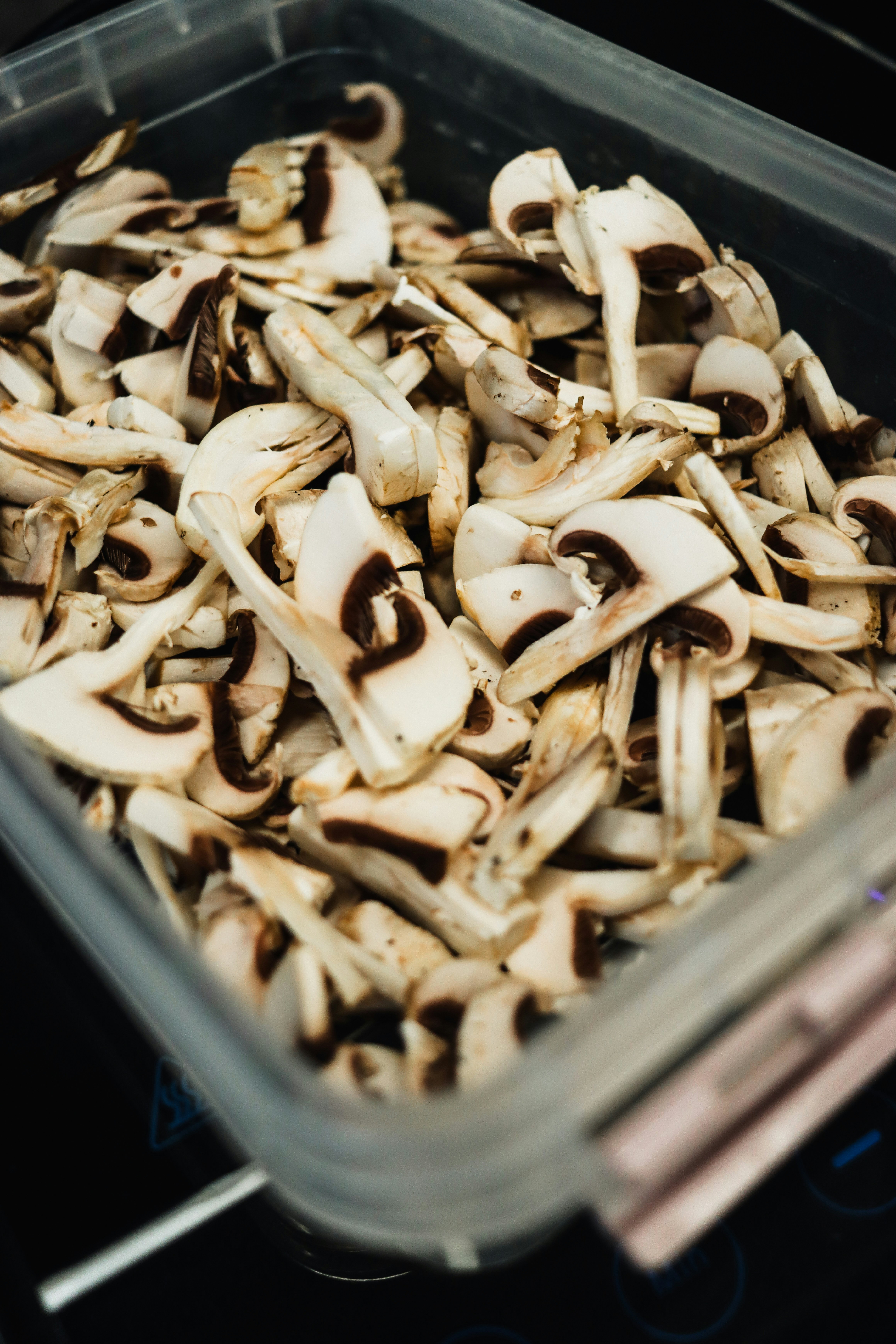 A plastic container filled with mushrooms sitting on top of a stove