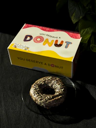 A donut sitting on a plate next to a box of donuts