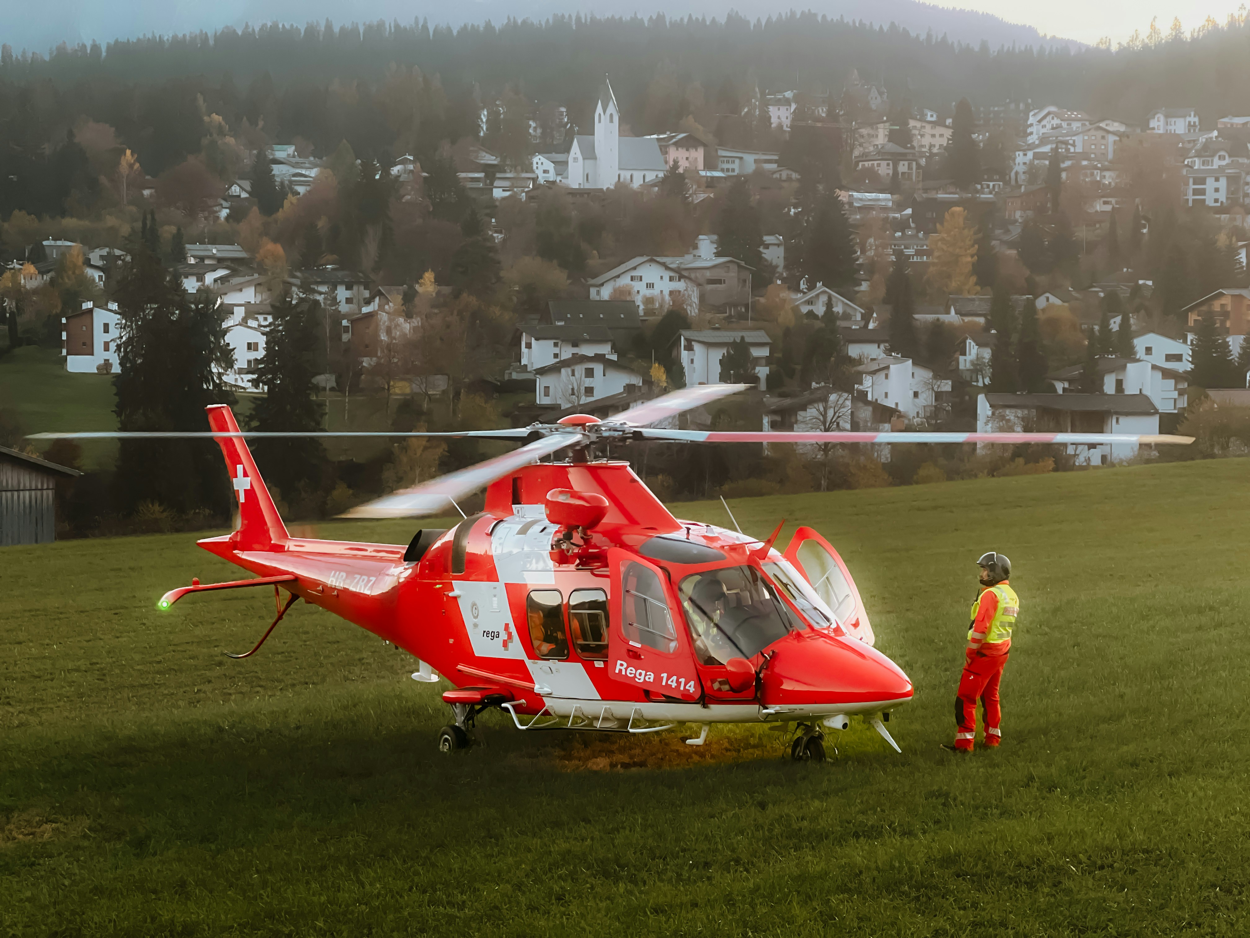 A man standing next to a helicopter on top of a lush green field
