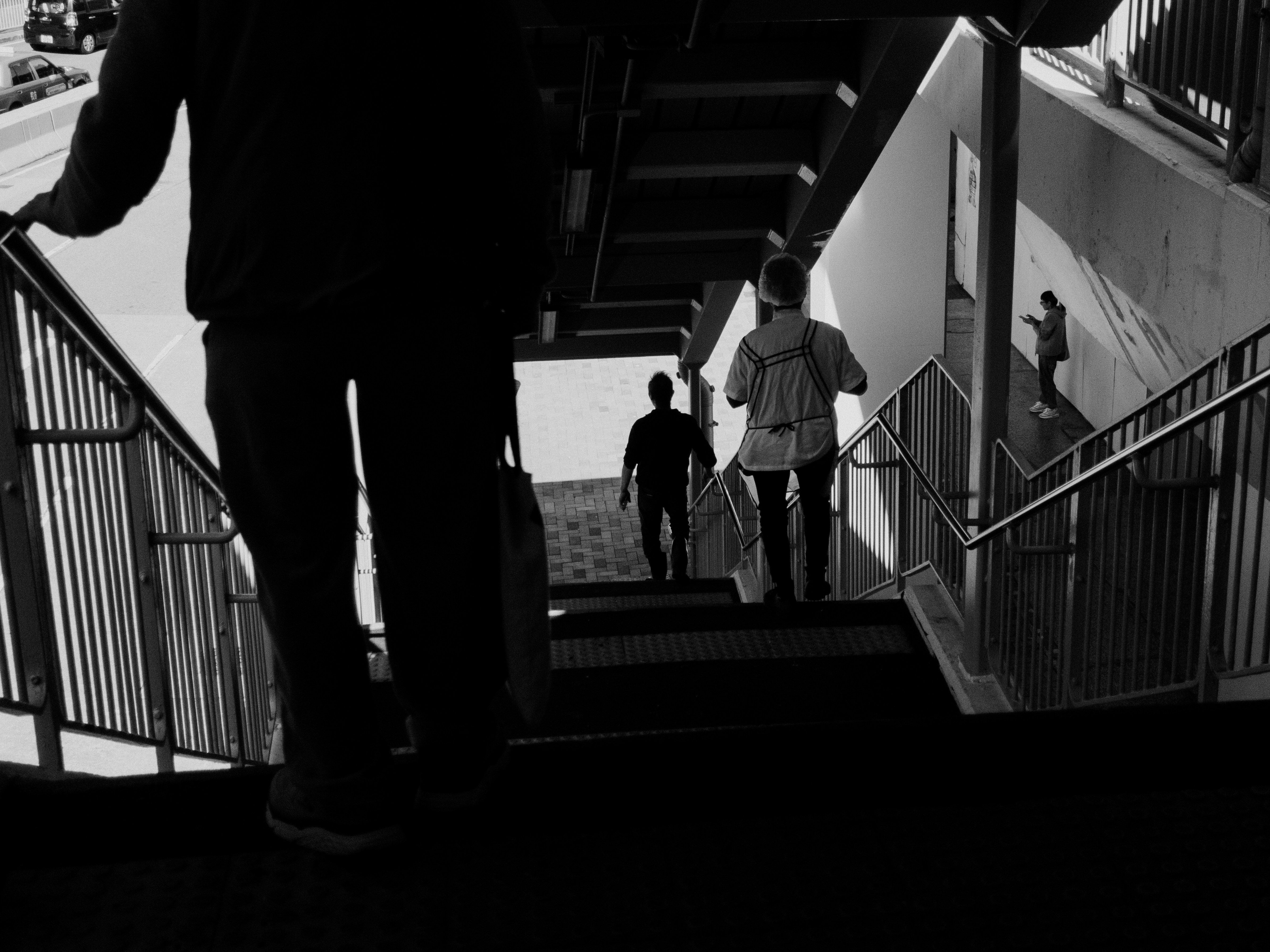 A black and white photo of a man walking up a flight of stairs