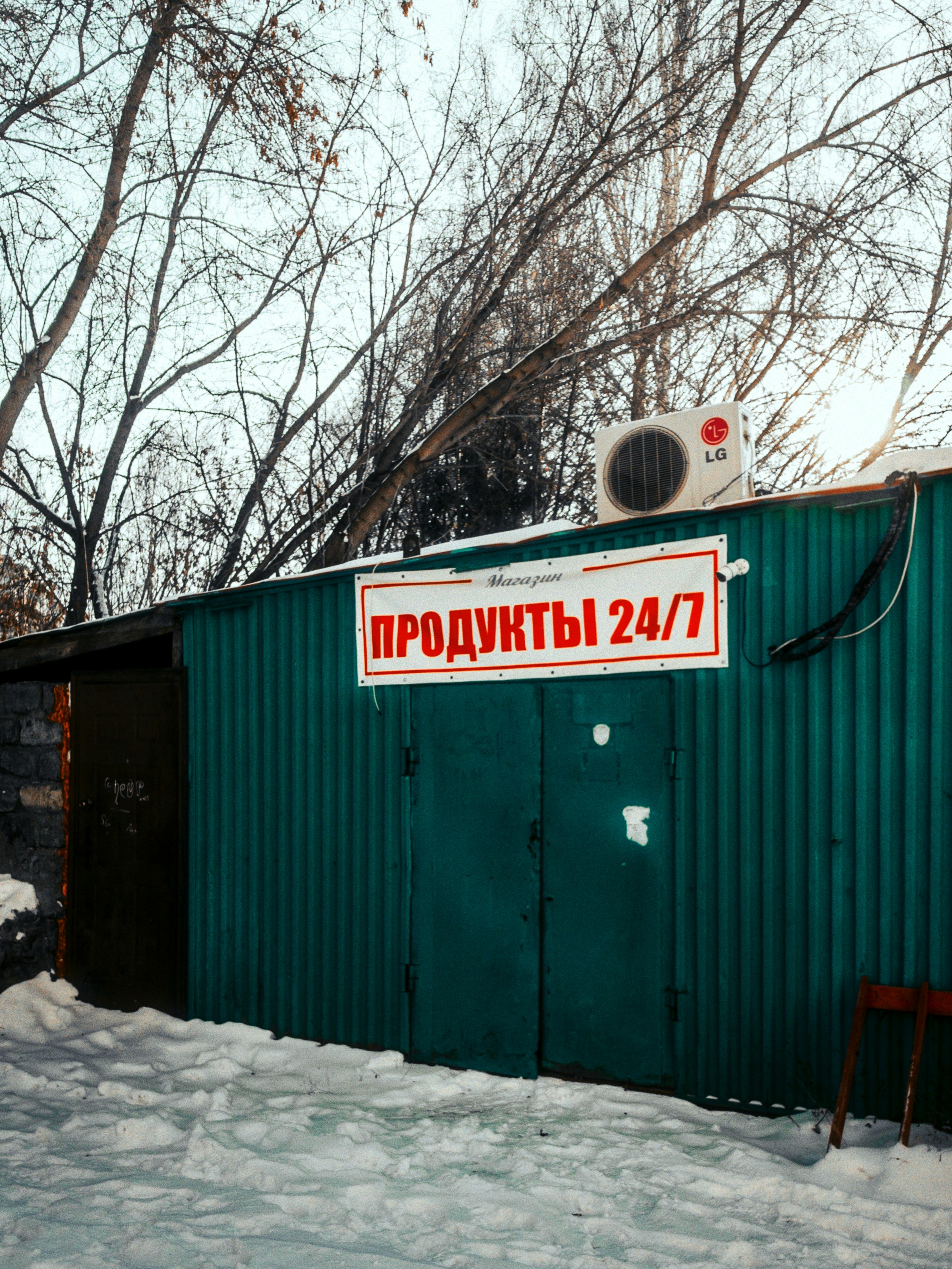 A green building with a sign on it in the snow