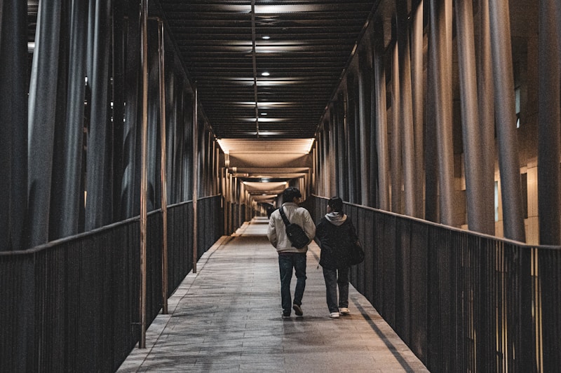 A couple of people walking down a long hallway