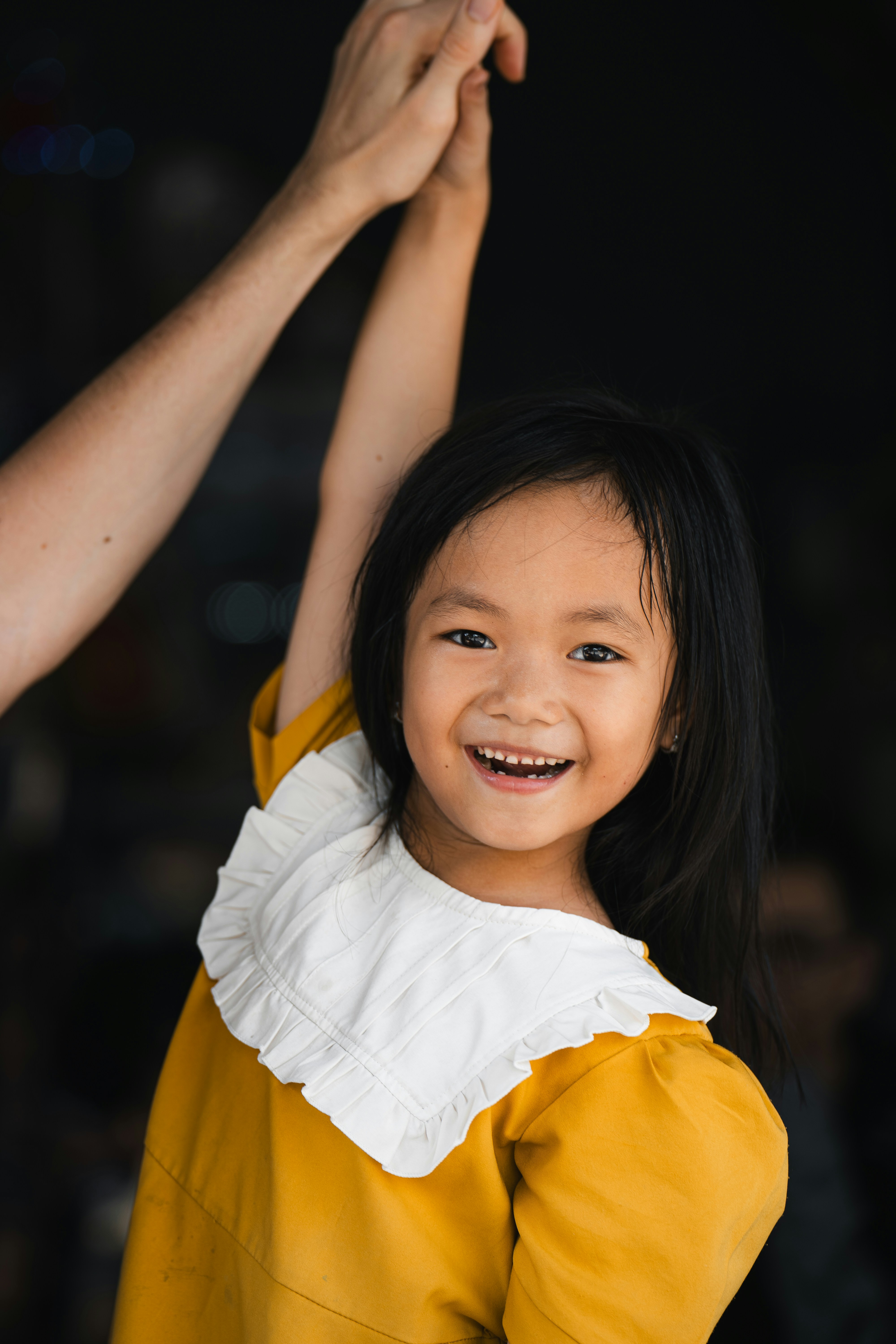 A little girl is holding the arm of an adult