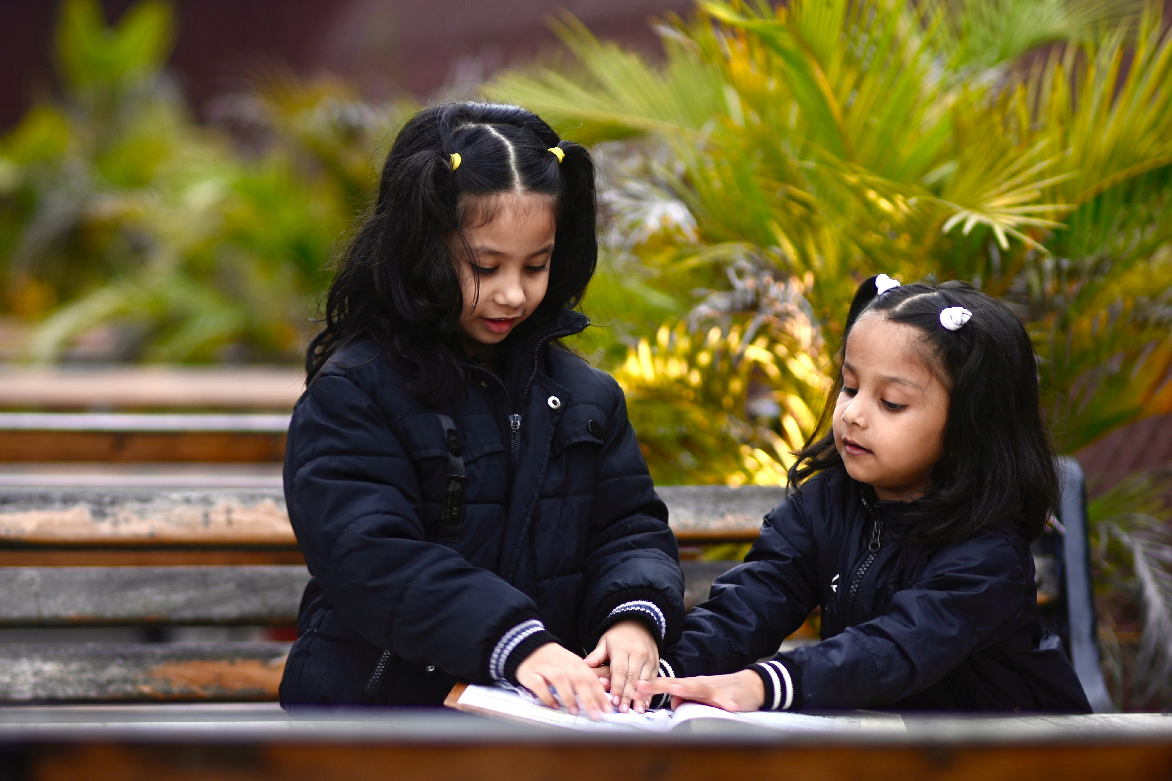 Two young girls sitting on a bench together