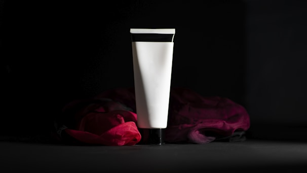 A white vase sitting next to a red rose