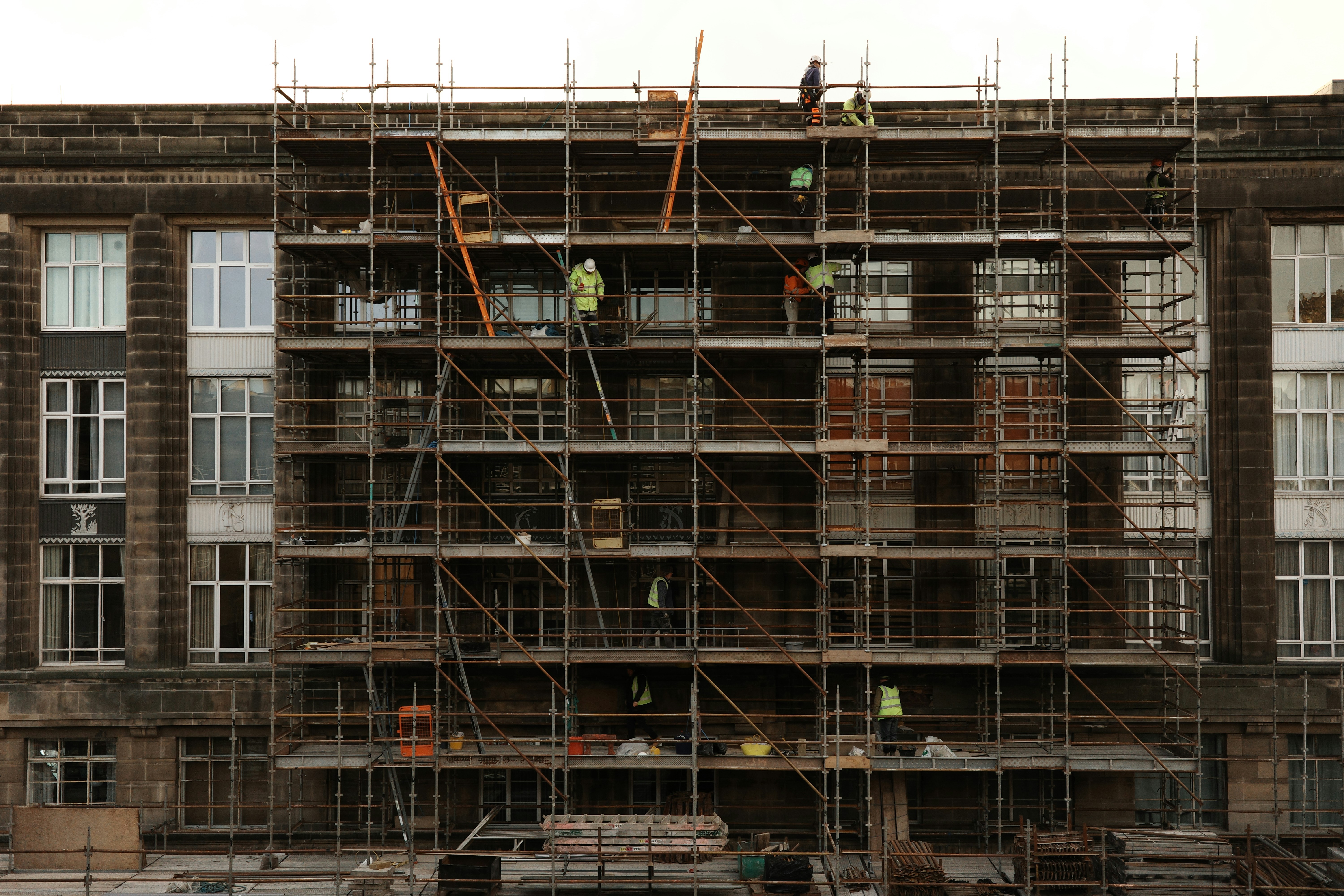 Commercial renovation site with workers in safety equipment, structural improvements in progress, professional environment