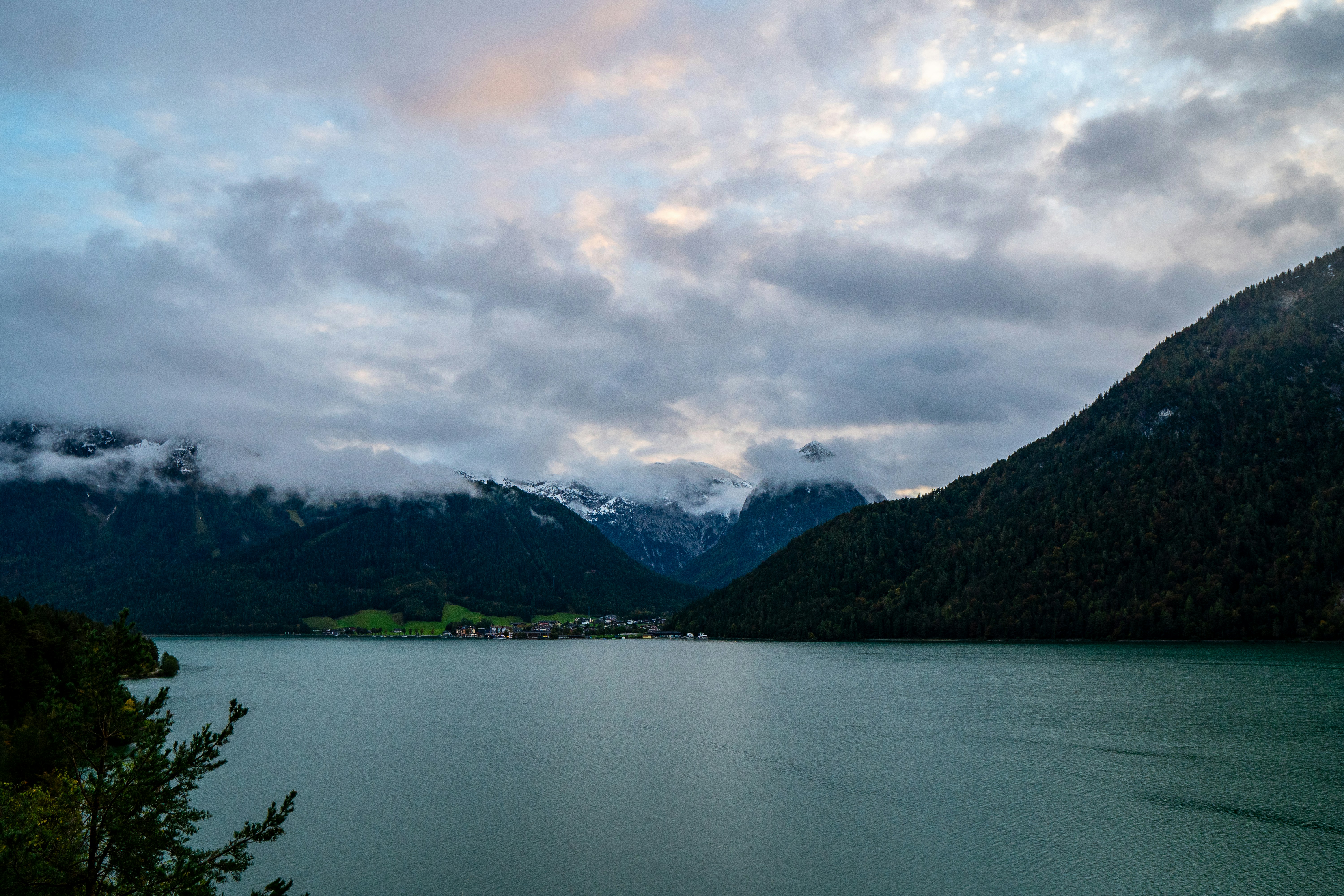 A body of water surrounded by mountains under a cloudy sky