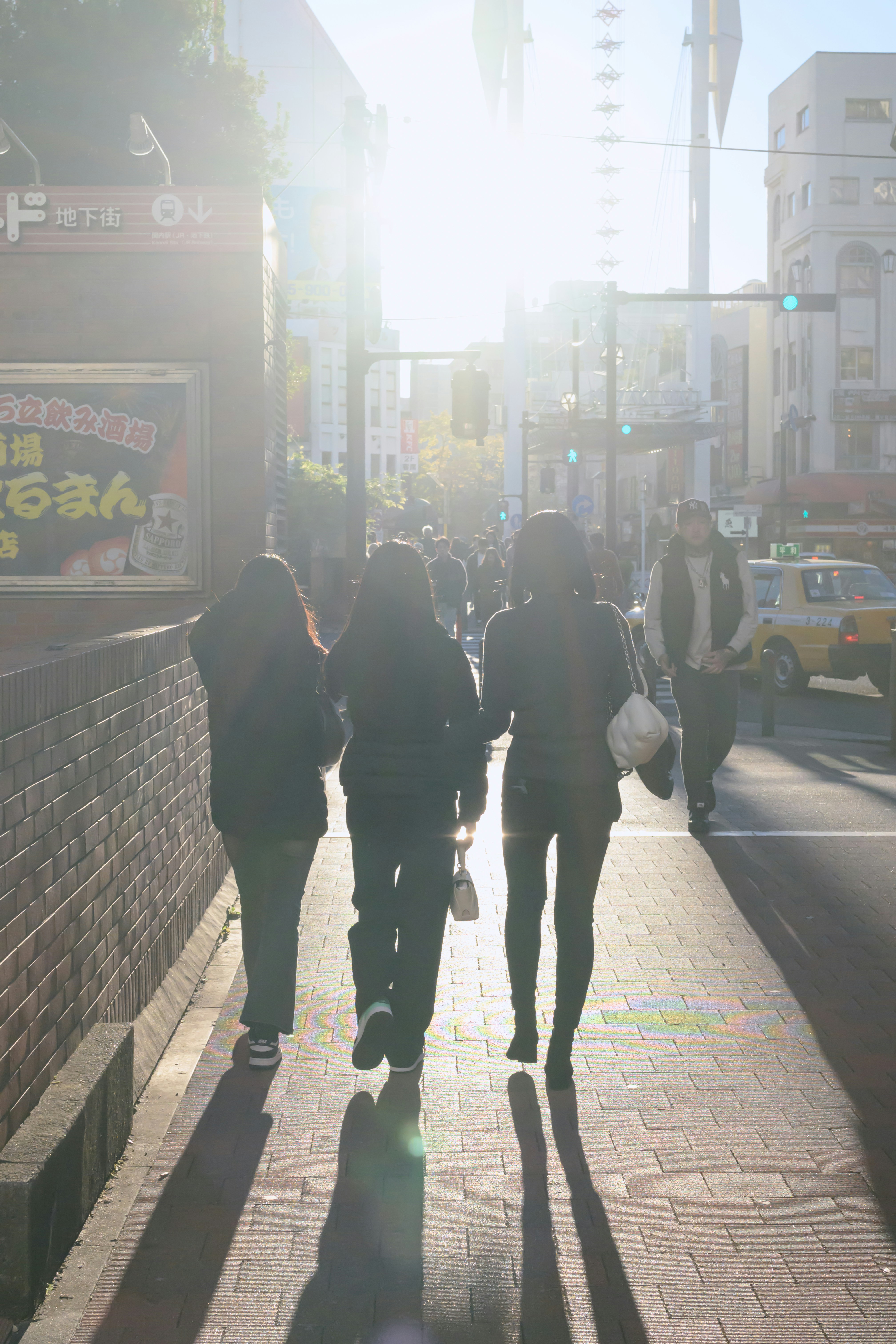 A group of people walking down a sidewalk