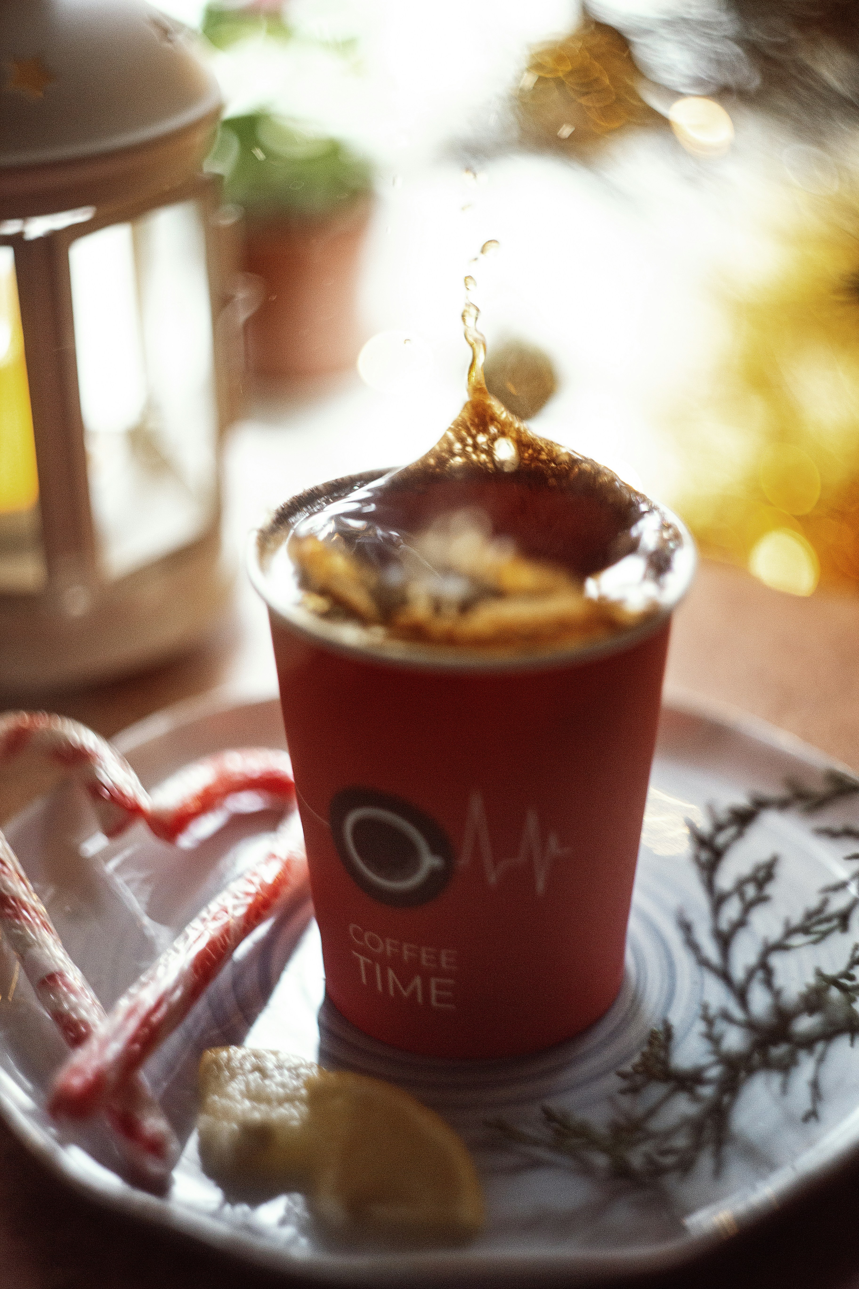 A cup of coffee on a plate with a candy cane