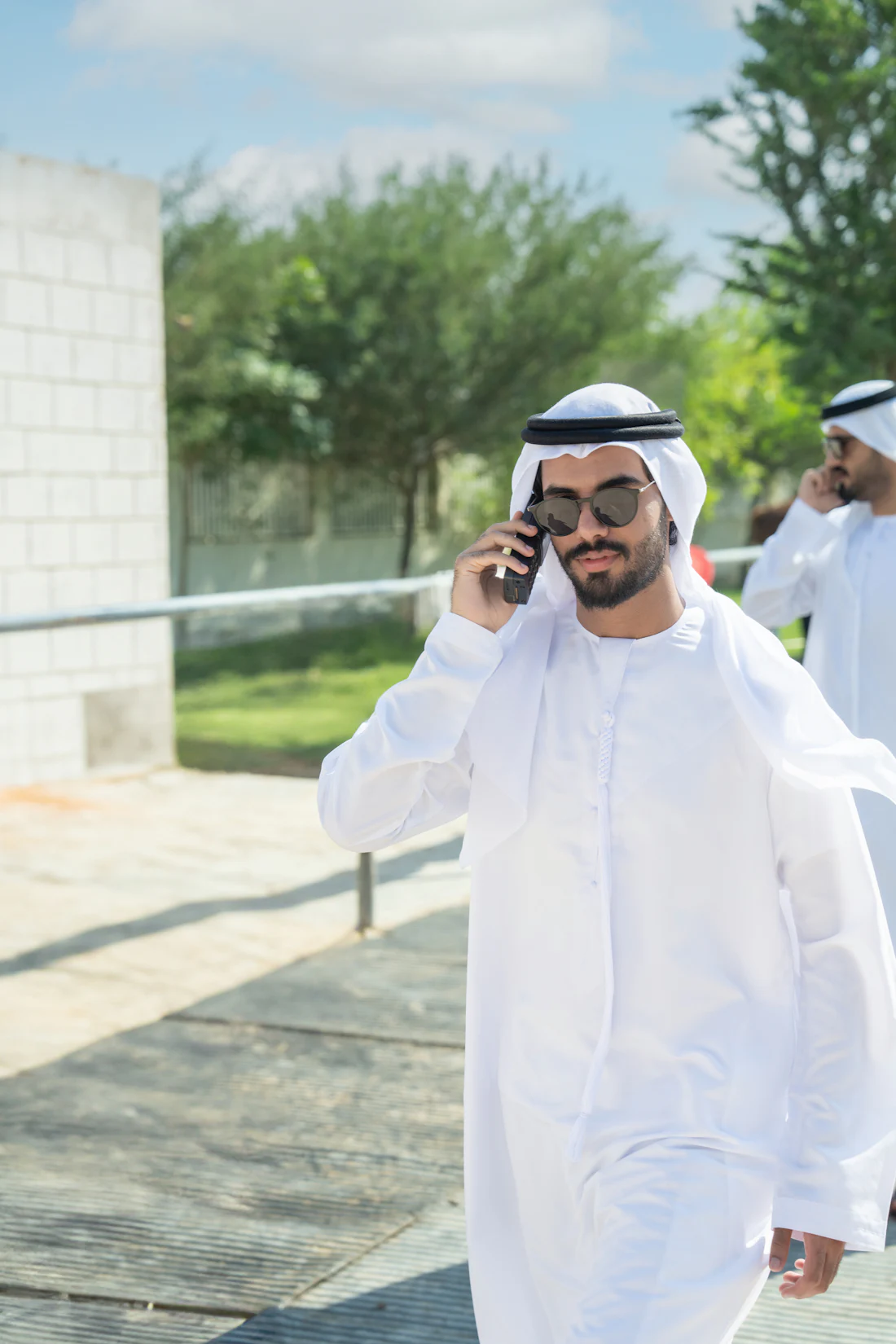A businessman in traditional Emirati dress walking while taking a phone call