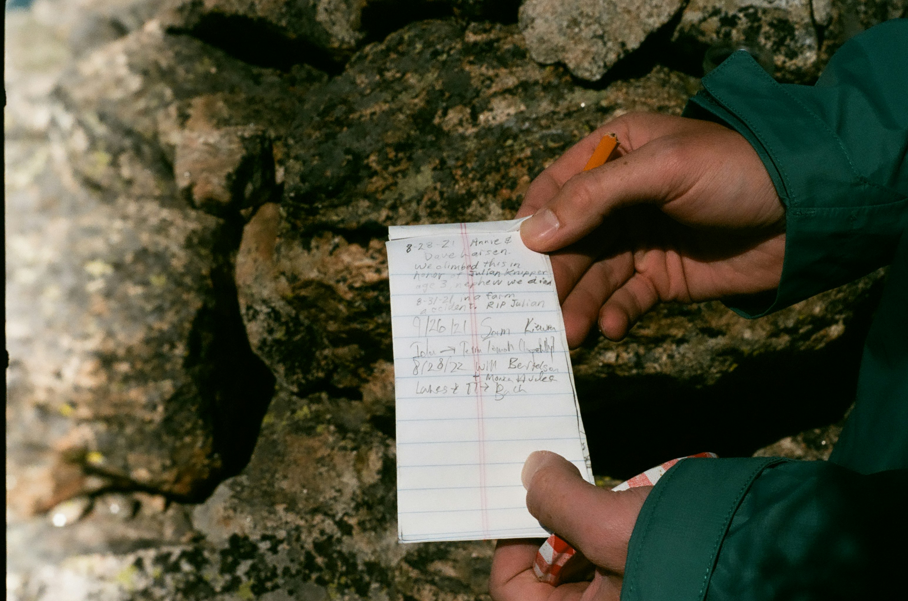 A person holding a piece of paper next to a rock