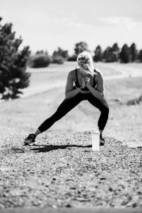 A black and white photo of a woman leaning on a pole