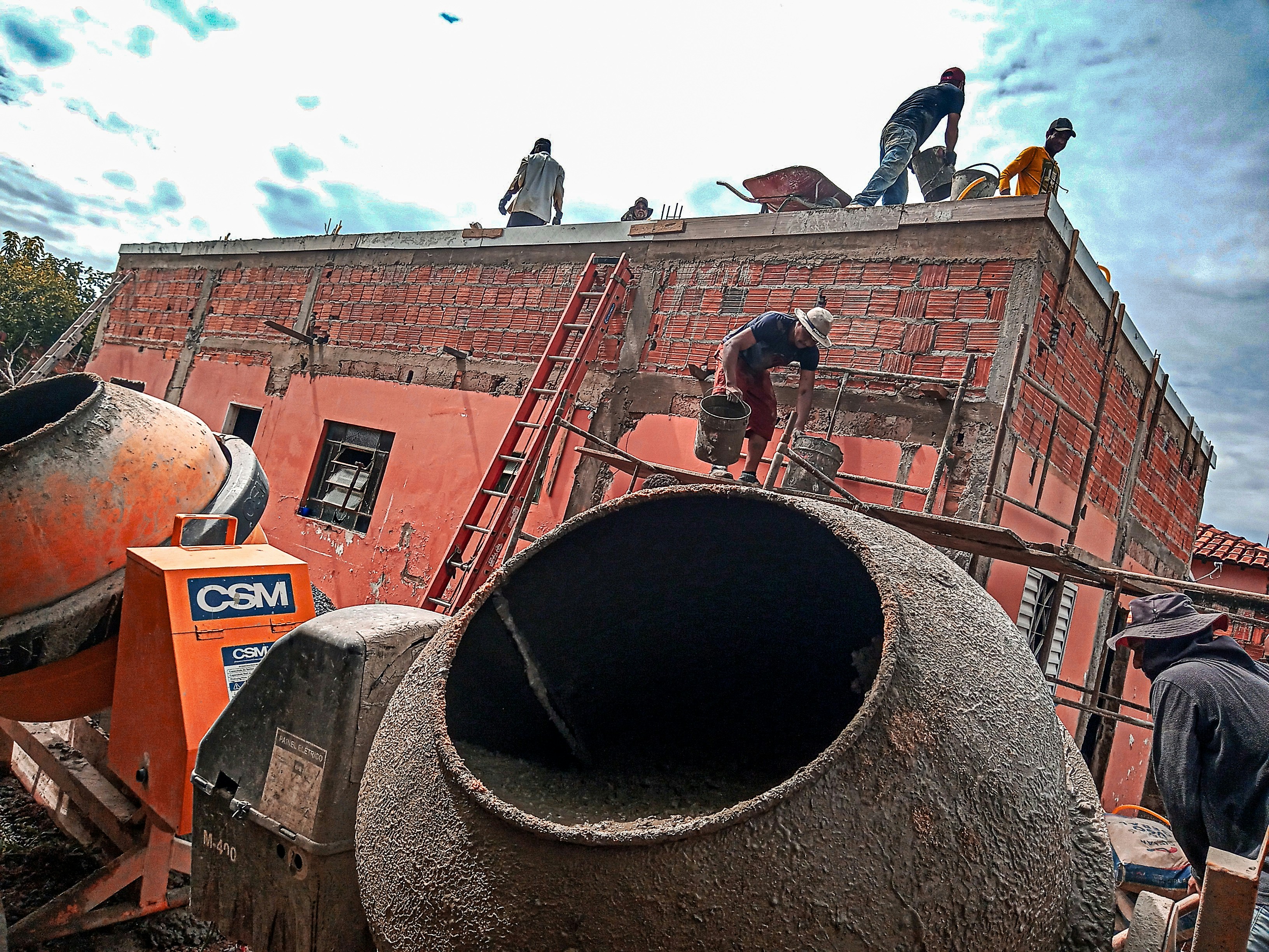 Concrete being poured from mixer truck at construction site, overcast sky, wet concrete surface, low-key dramatic atmosphere