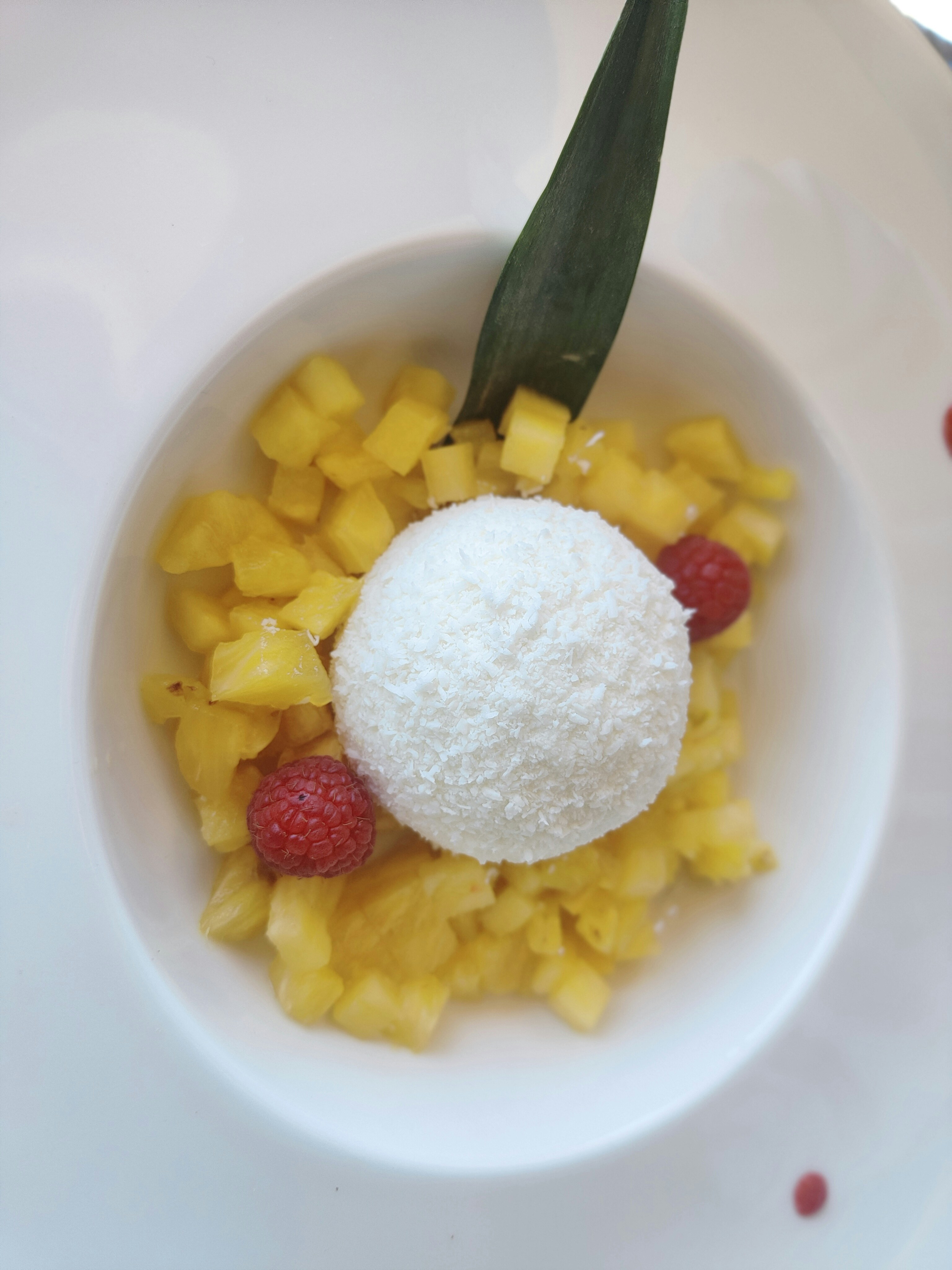 White coconut lychee ice cream in a pint container with whole lychee fruits and coconut shavings