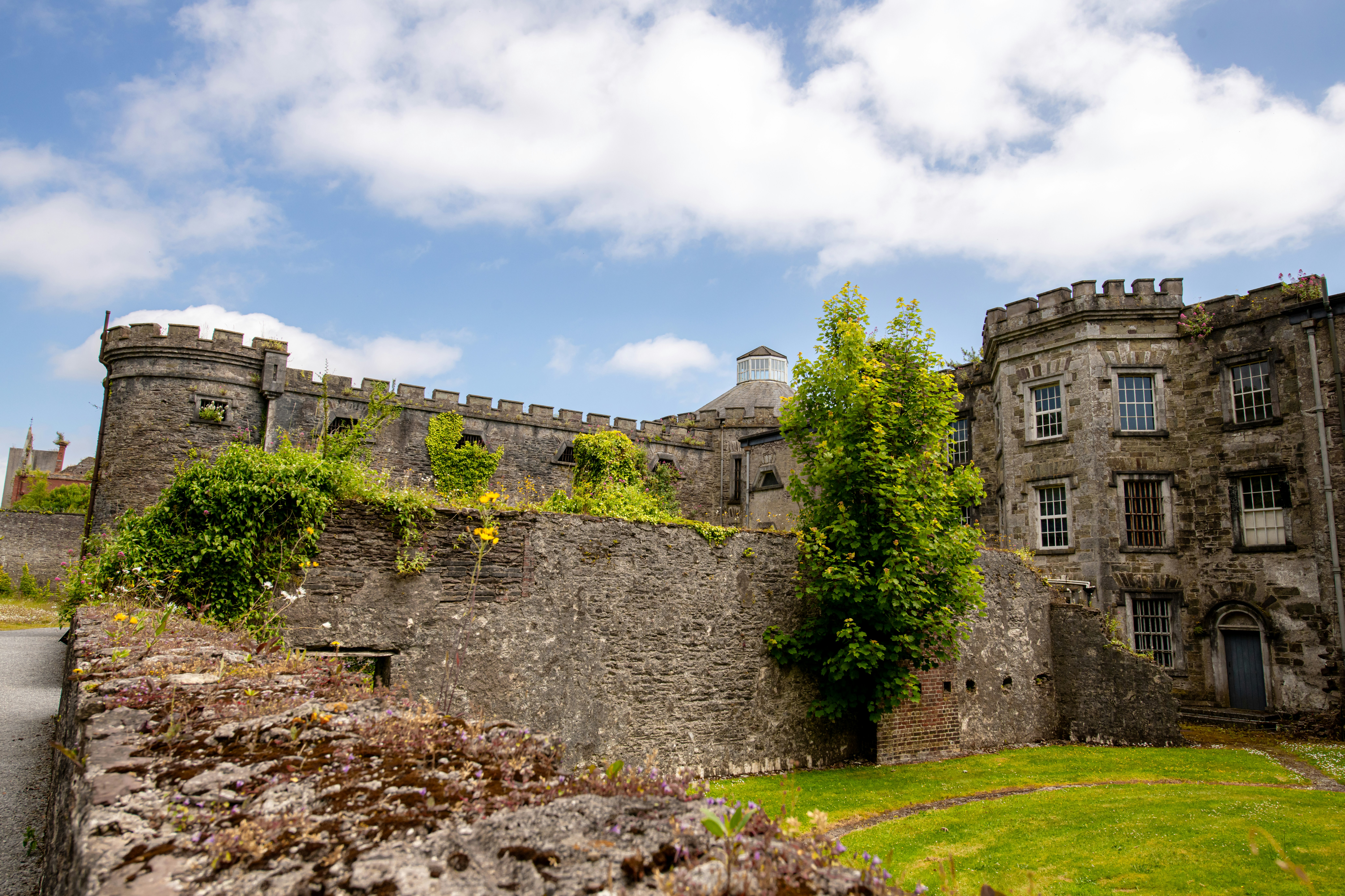 A castle with a stone wall and a green lawn