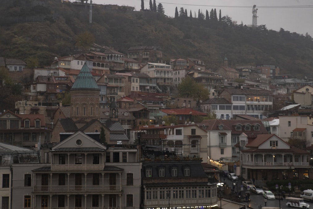 Old Tbilisi rooftops stacked up the hillside with the Caucasus mountains rising behind