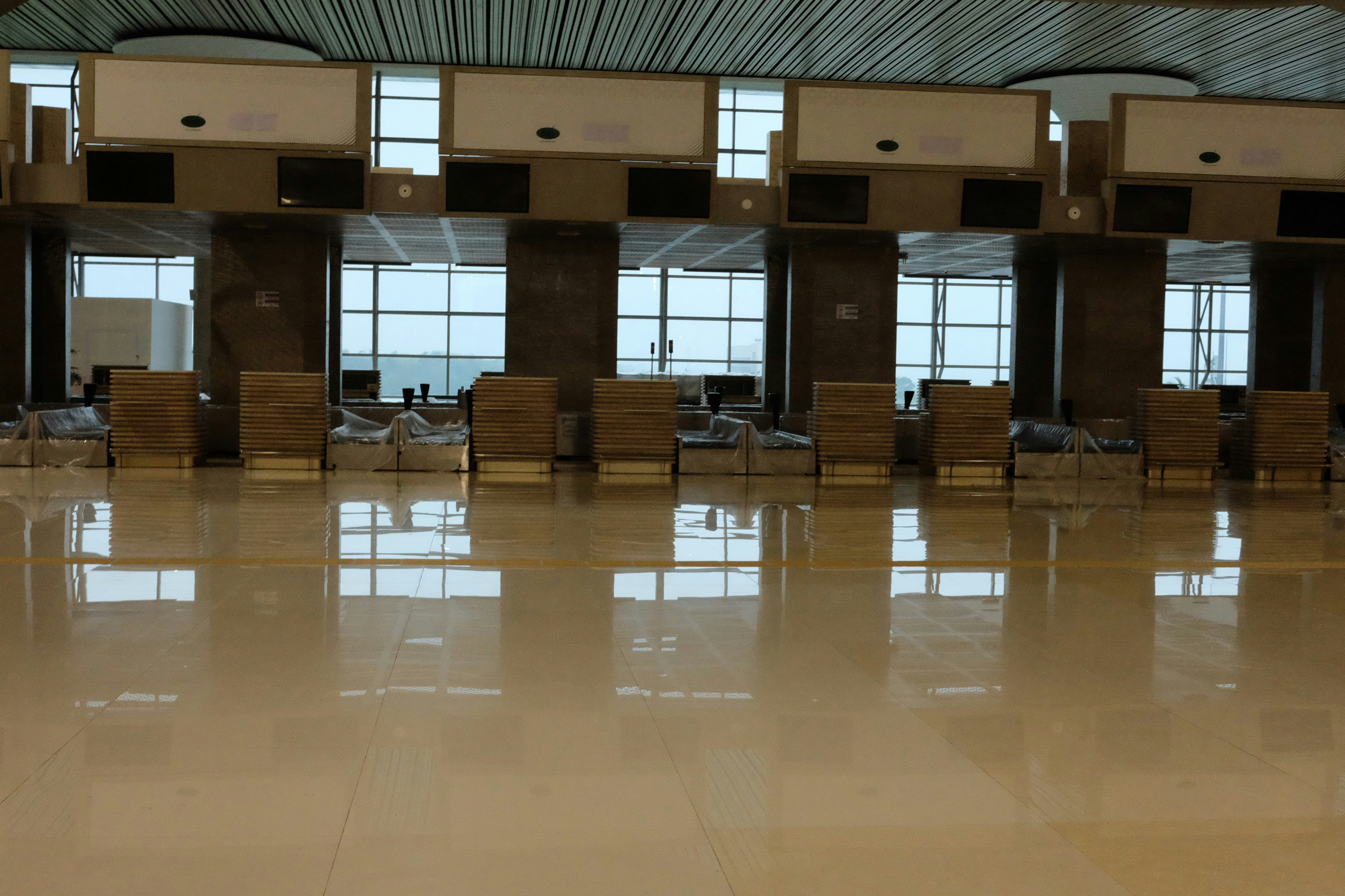 A large room with lots of chairs and windows, check in kiosk airport