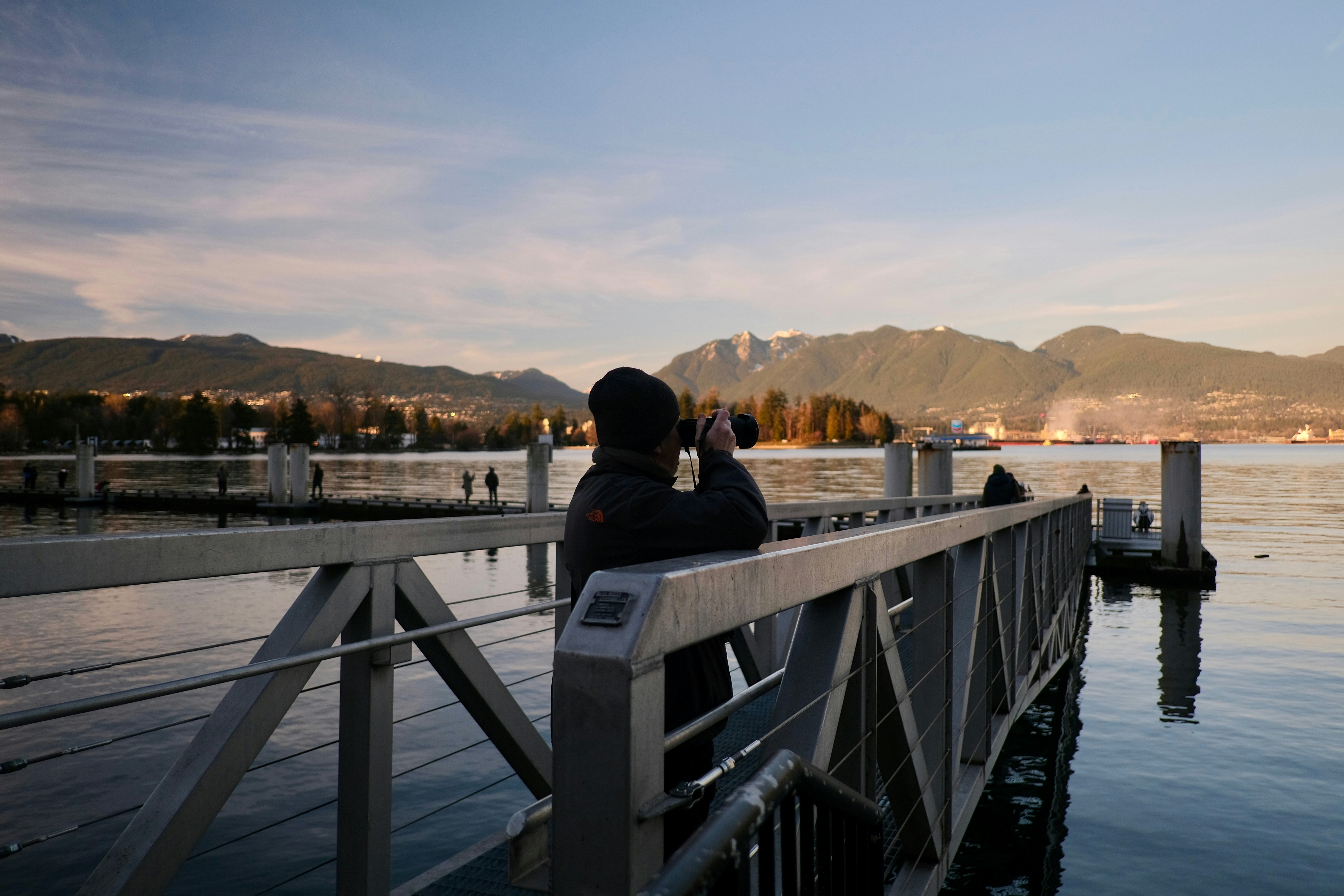 A person sitting on a dock with a cell phone to their ear