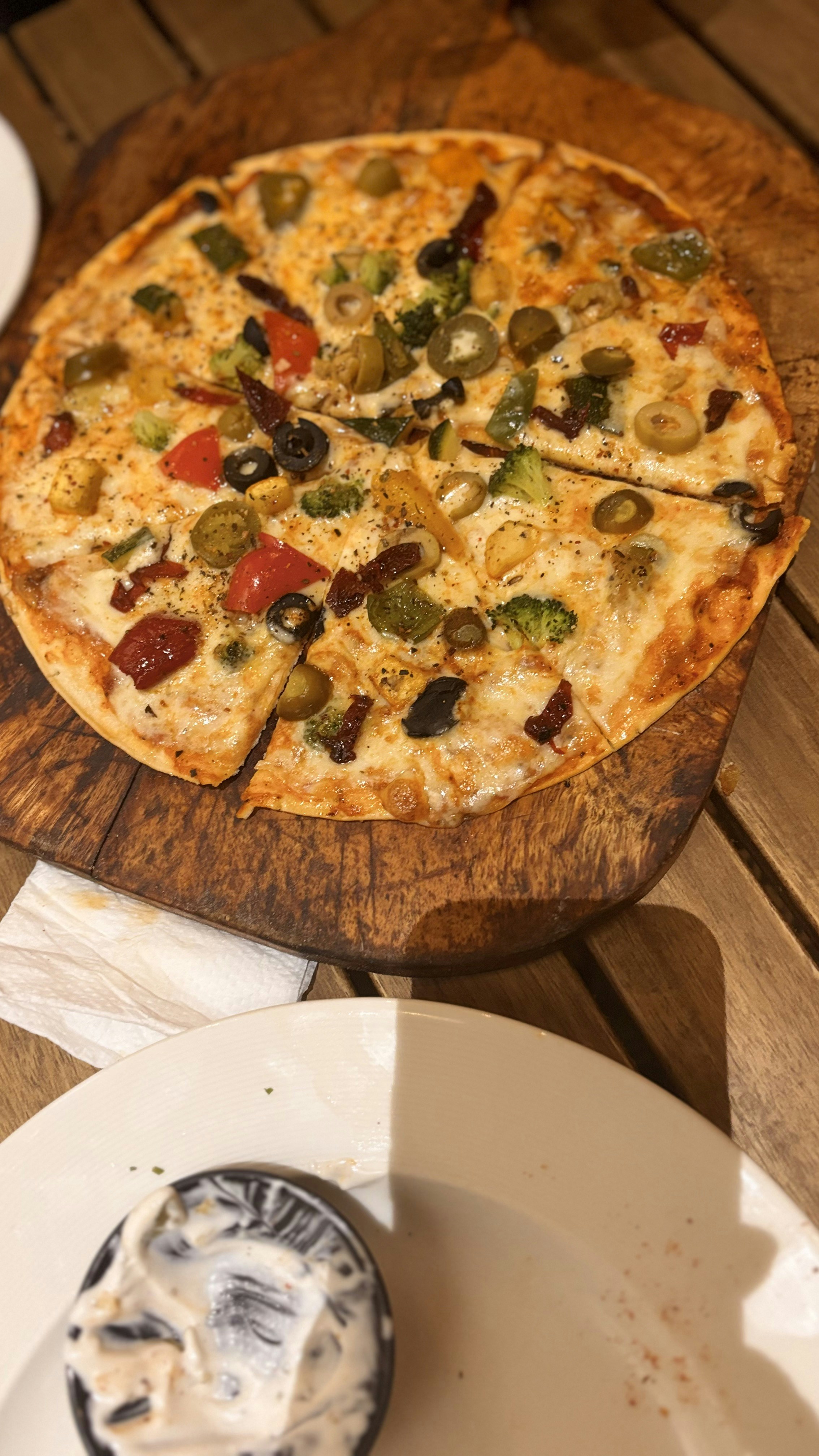 Freshly baked pizza slice on wooden board with herbs and cheese