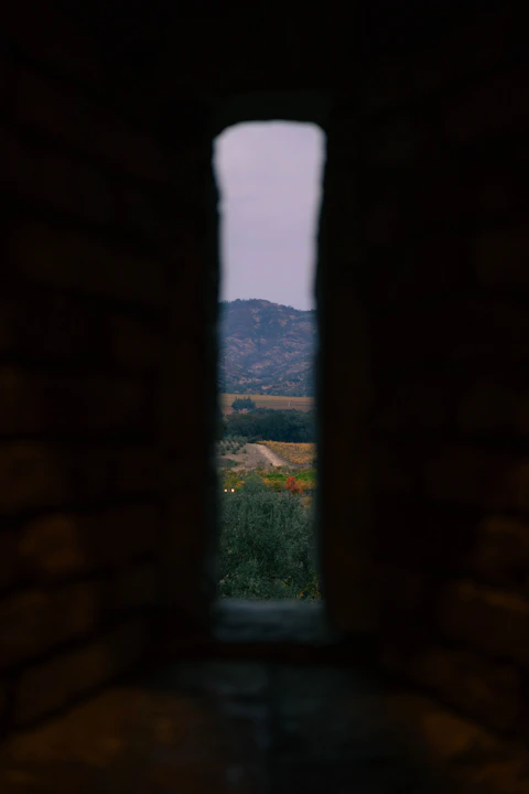 A window in a stone building with a view of mountains