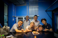 A group of people standing around a table with a cake