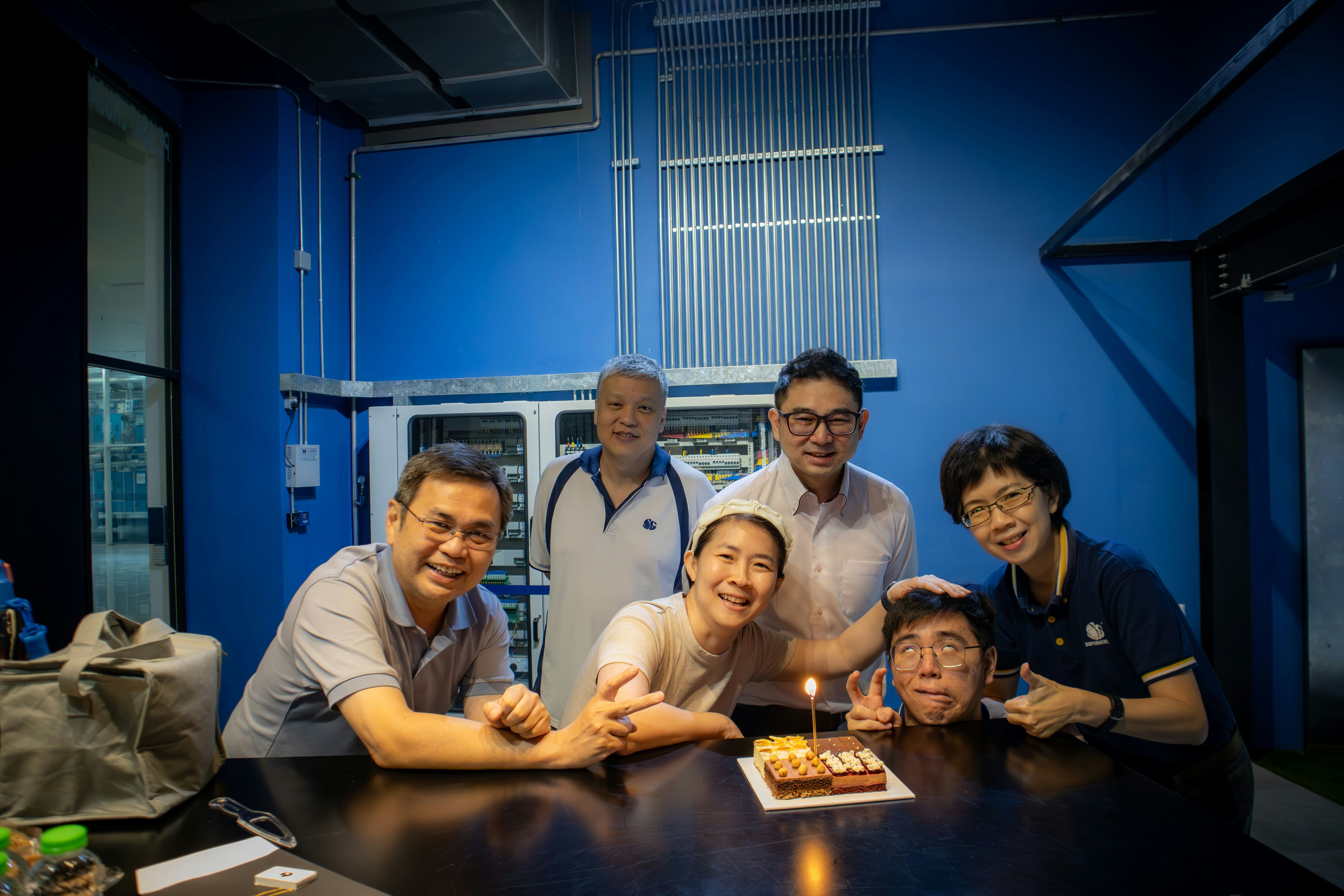 A group of people standing around a table with a cake