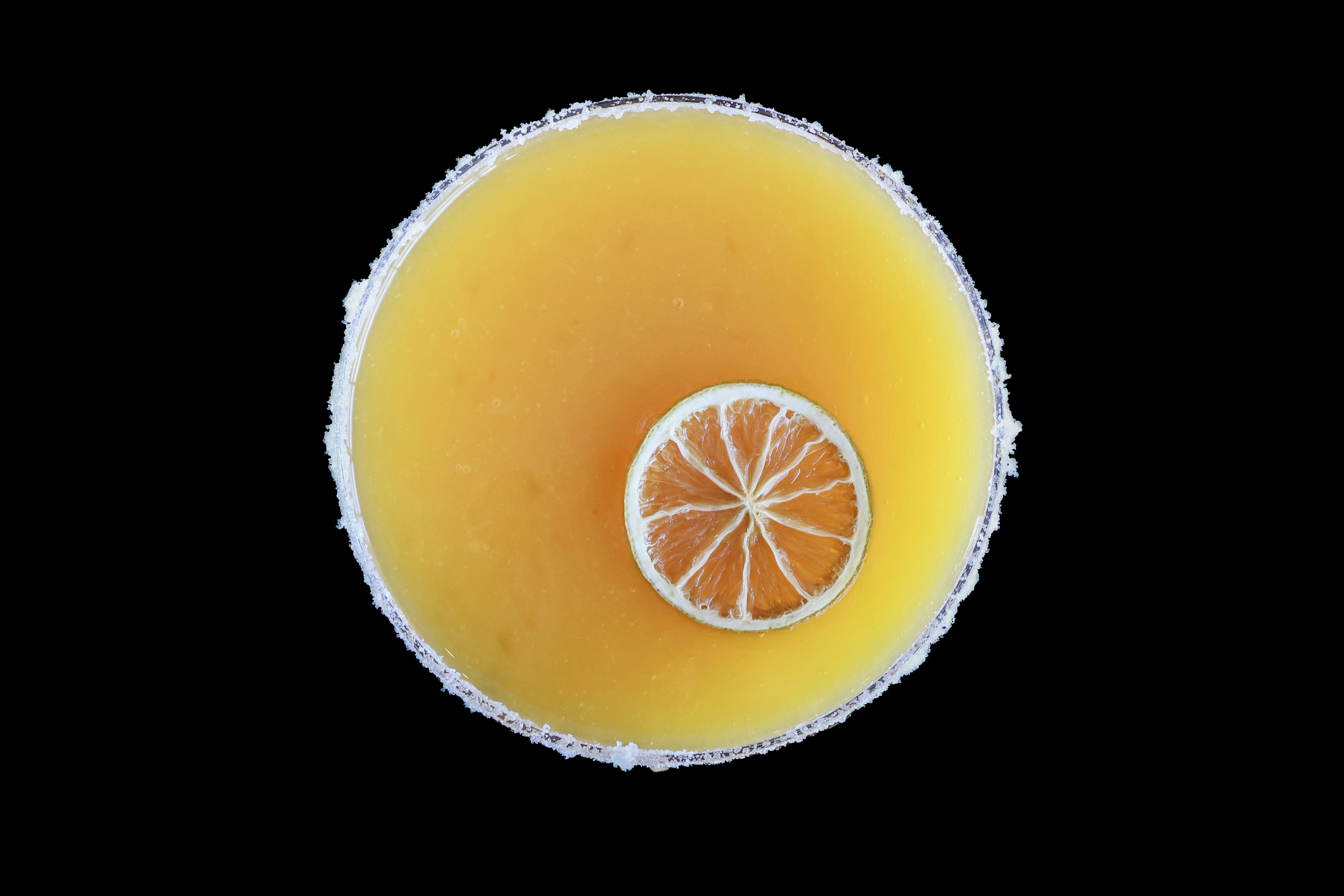 A glass of orange juice with a slice taken out of it