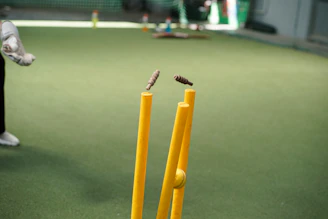 A man standing next to a yellow bat and ball