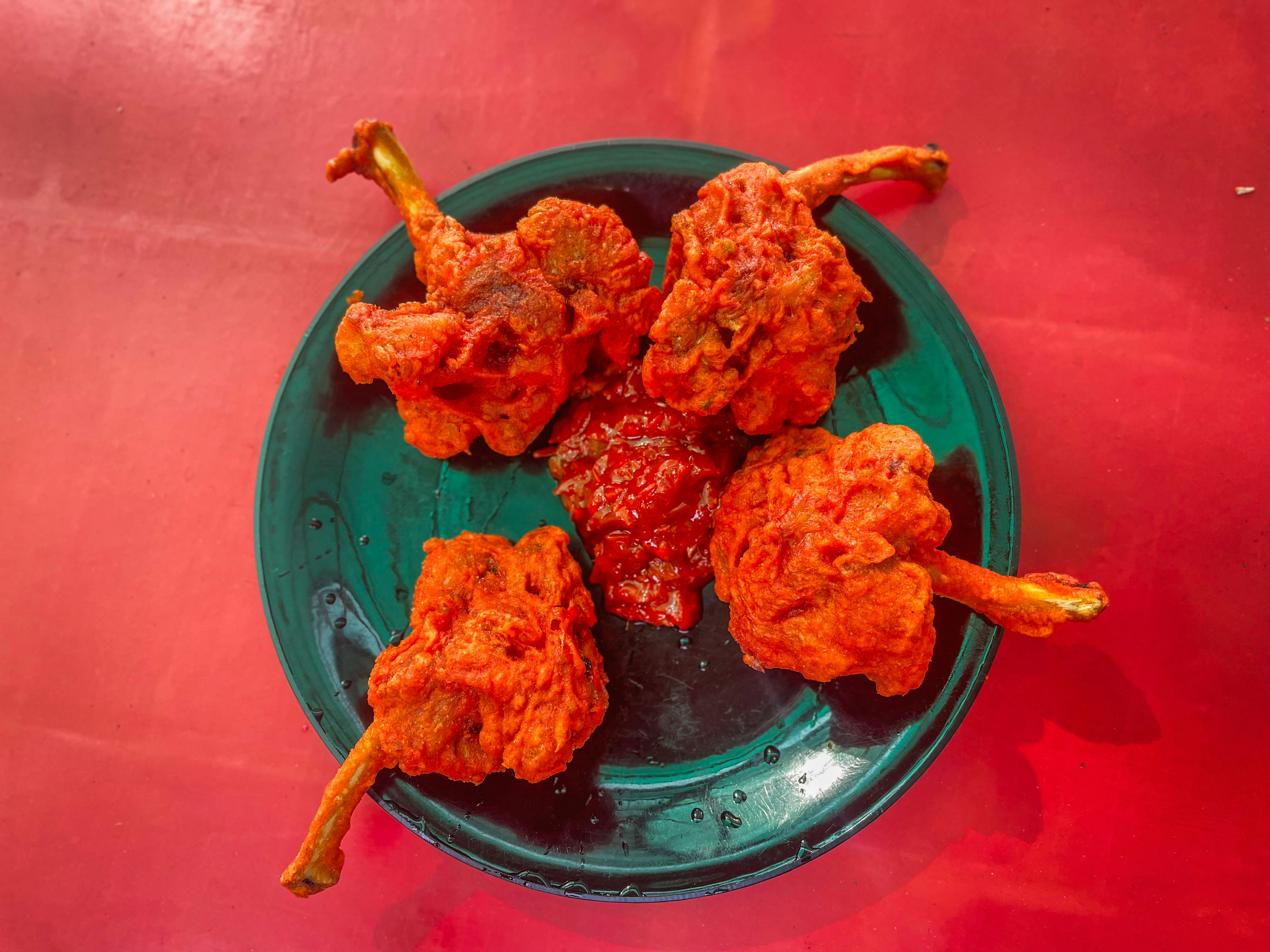 Golden crispy seafood lollipops on dark slate plate with red chutney — dramatic low-key lighting