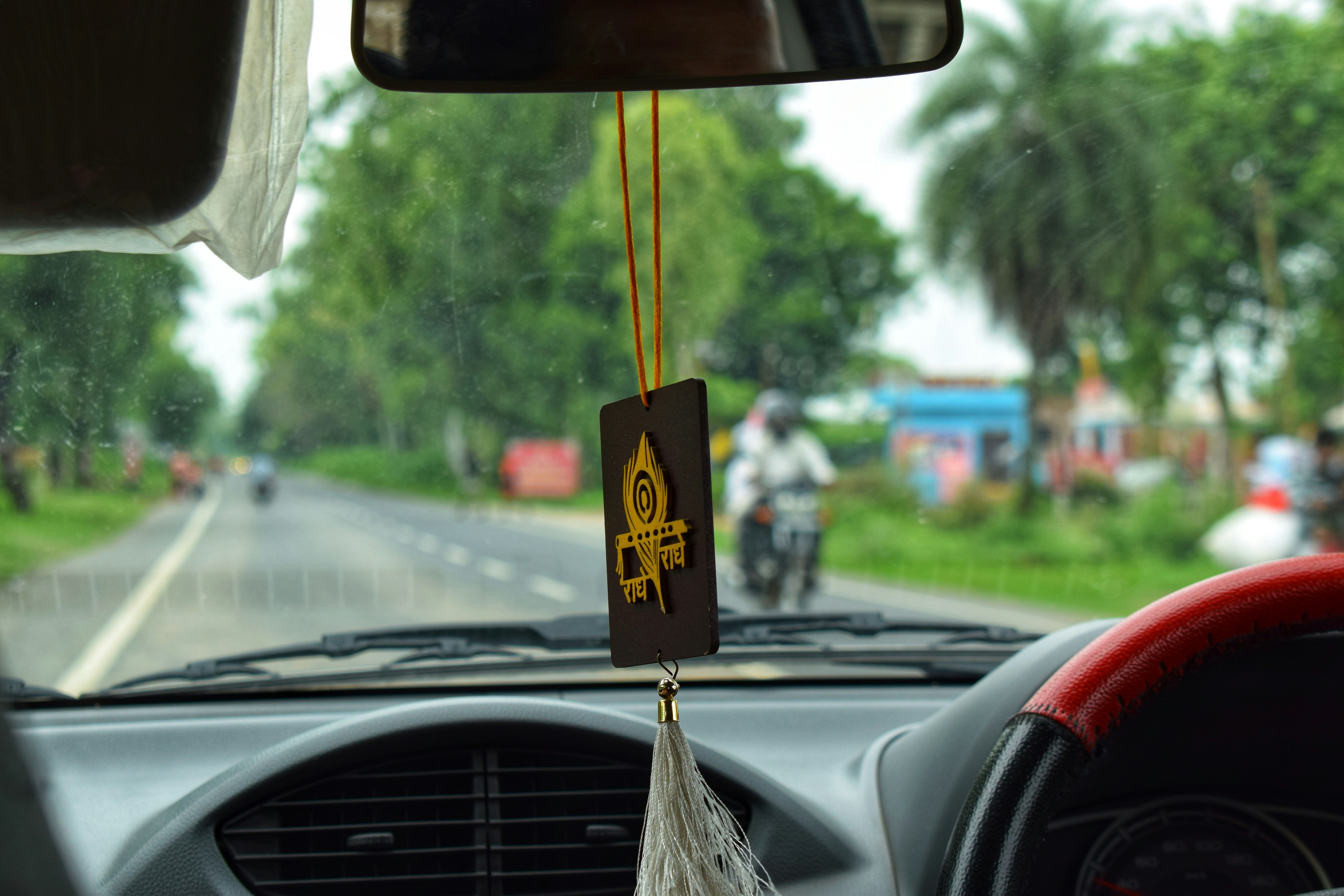 A view from inside a car of a man riding a motorcycle
