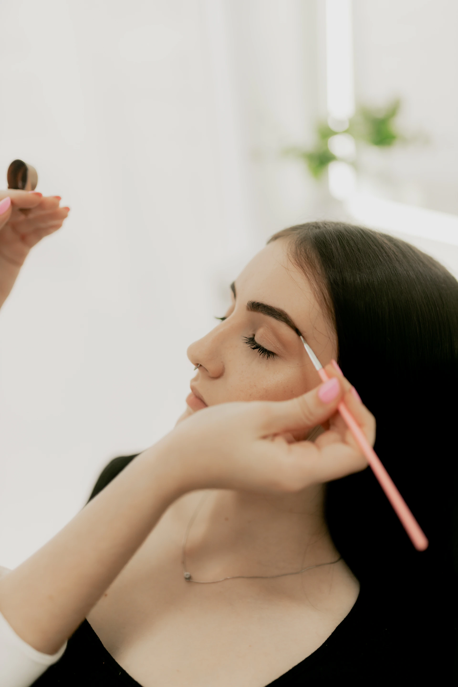A woman is doing makeup on her face