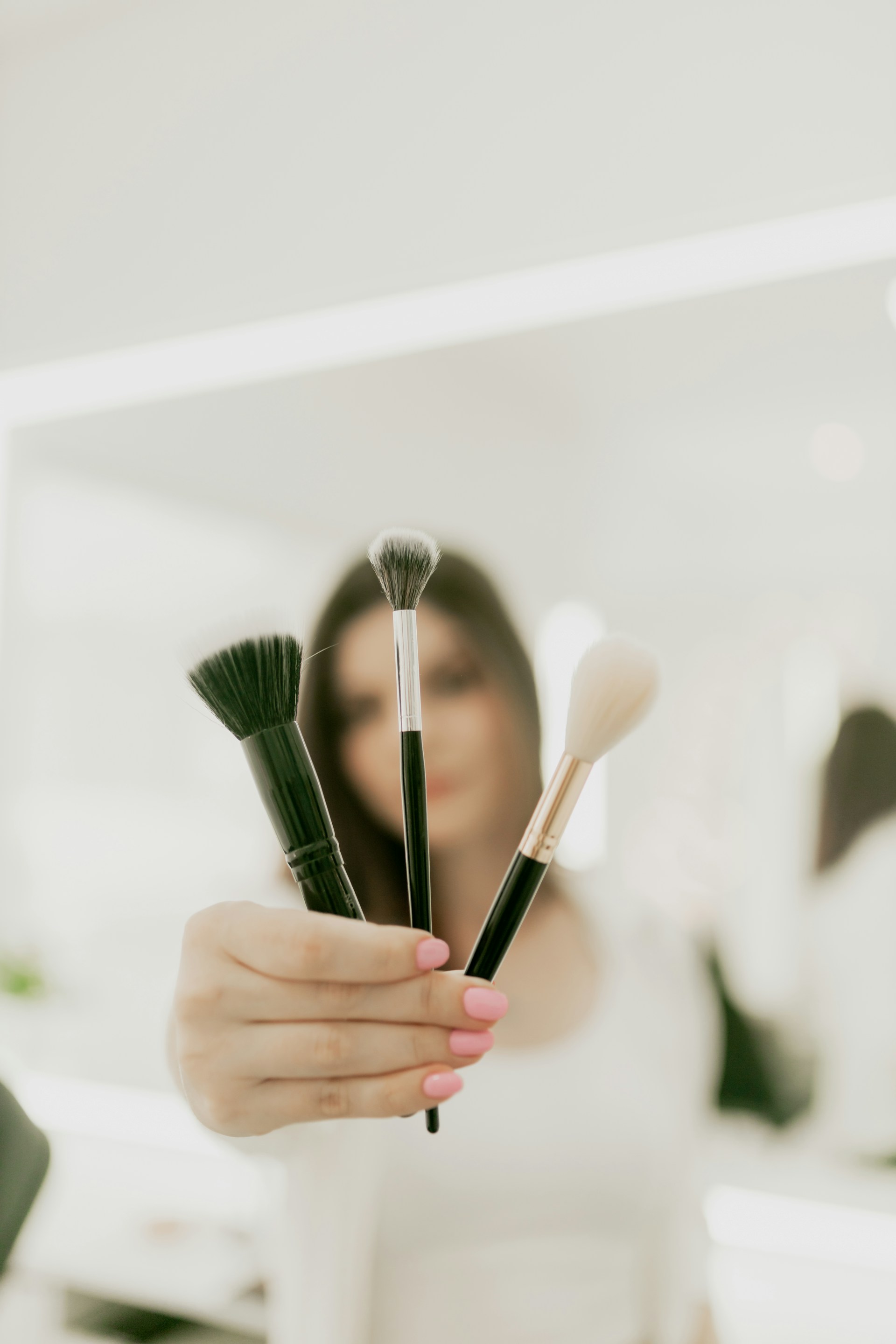 A woman holding a bunch of makeup brushes in her hand