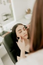 A woman sitting in a chair looking at her reflection in the mirror