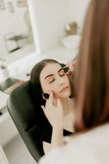 A woman sitting in a chair looking at her reflection in the mirror
