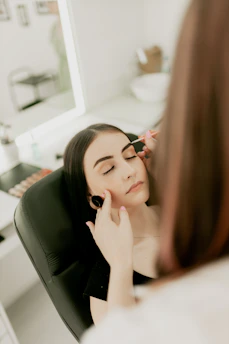 A woman sitting in a chair looking at her reflection in the mirror