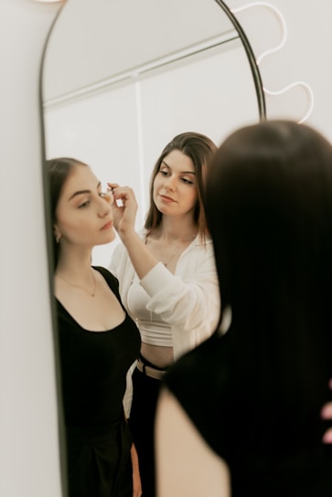 A woman standing in front of a mirror brushing her teeth