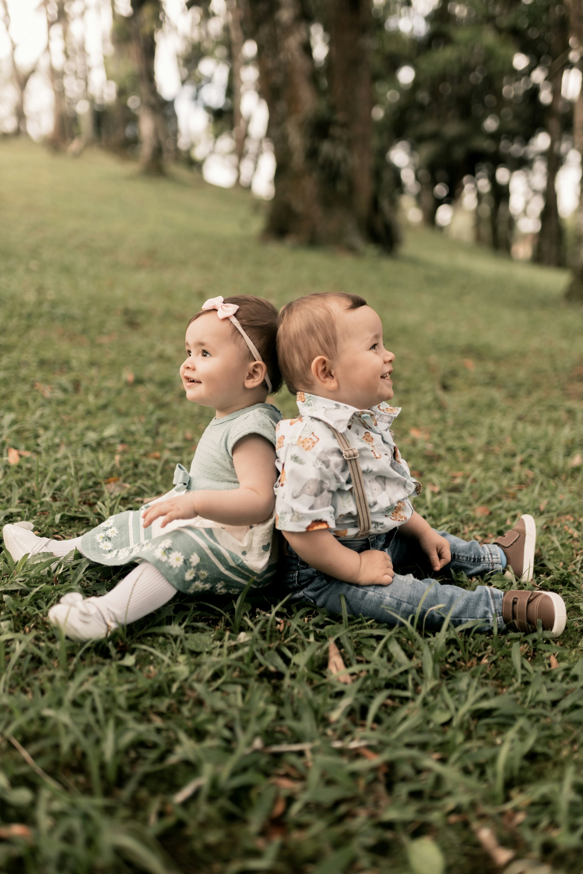 Two small children sitting on the ground in the grass
