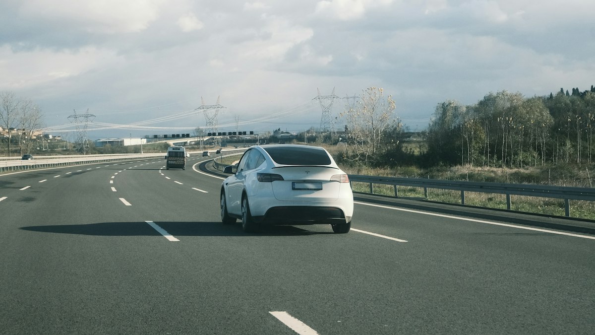 Weißes Auto auf einer Autobahn unter bewölktem Himmel