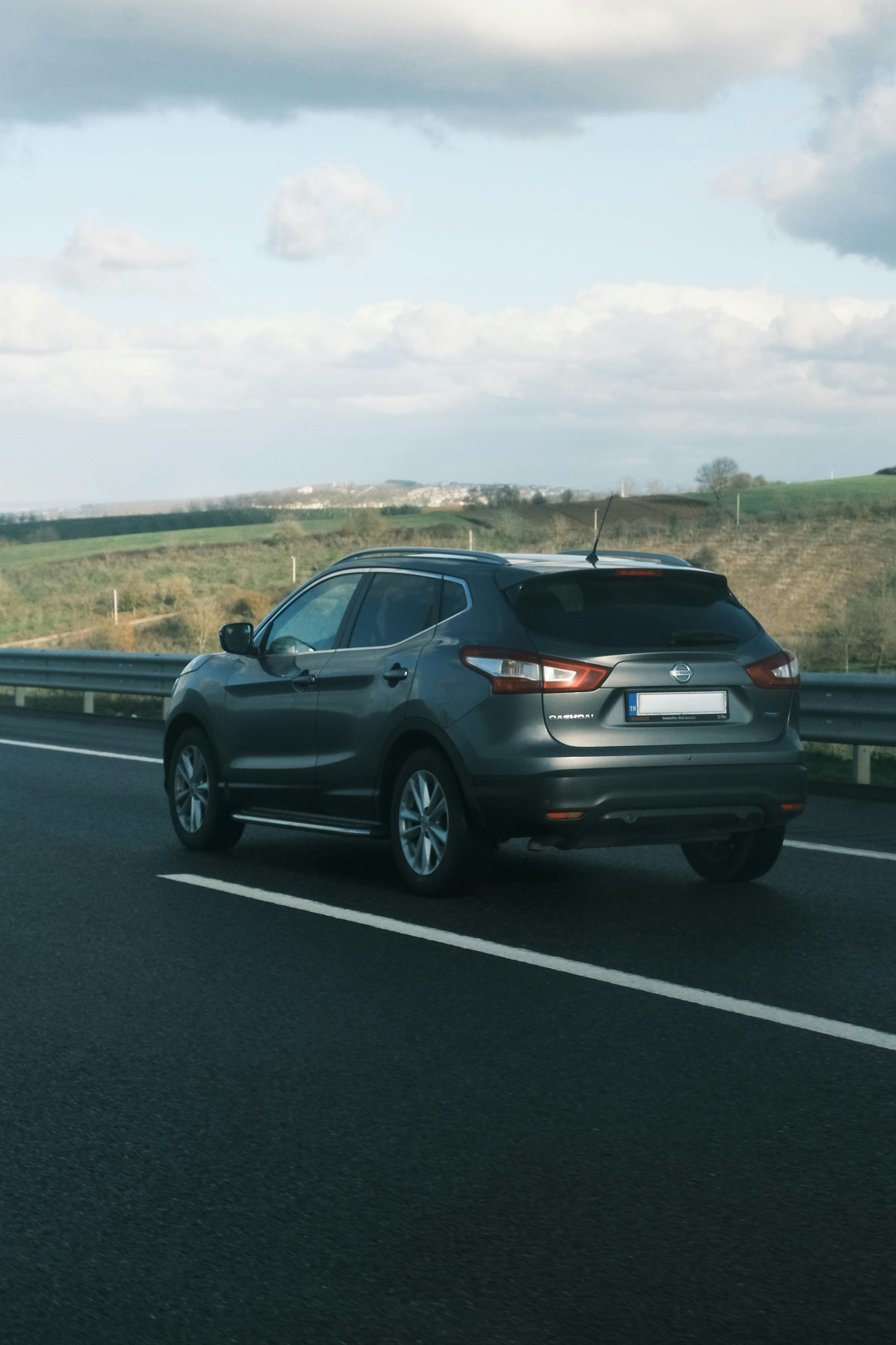A car driving down a highway next to a field