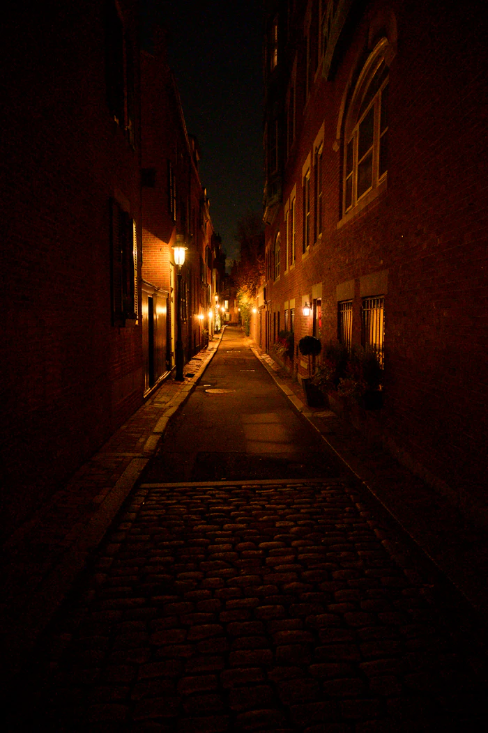 A dark alley at night with street lights on