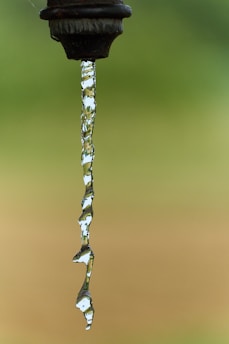 A black faucet with water running down it