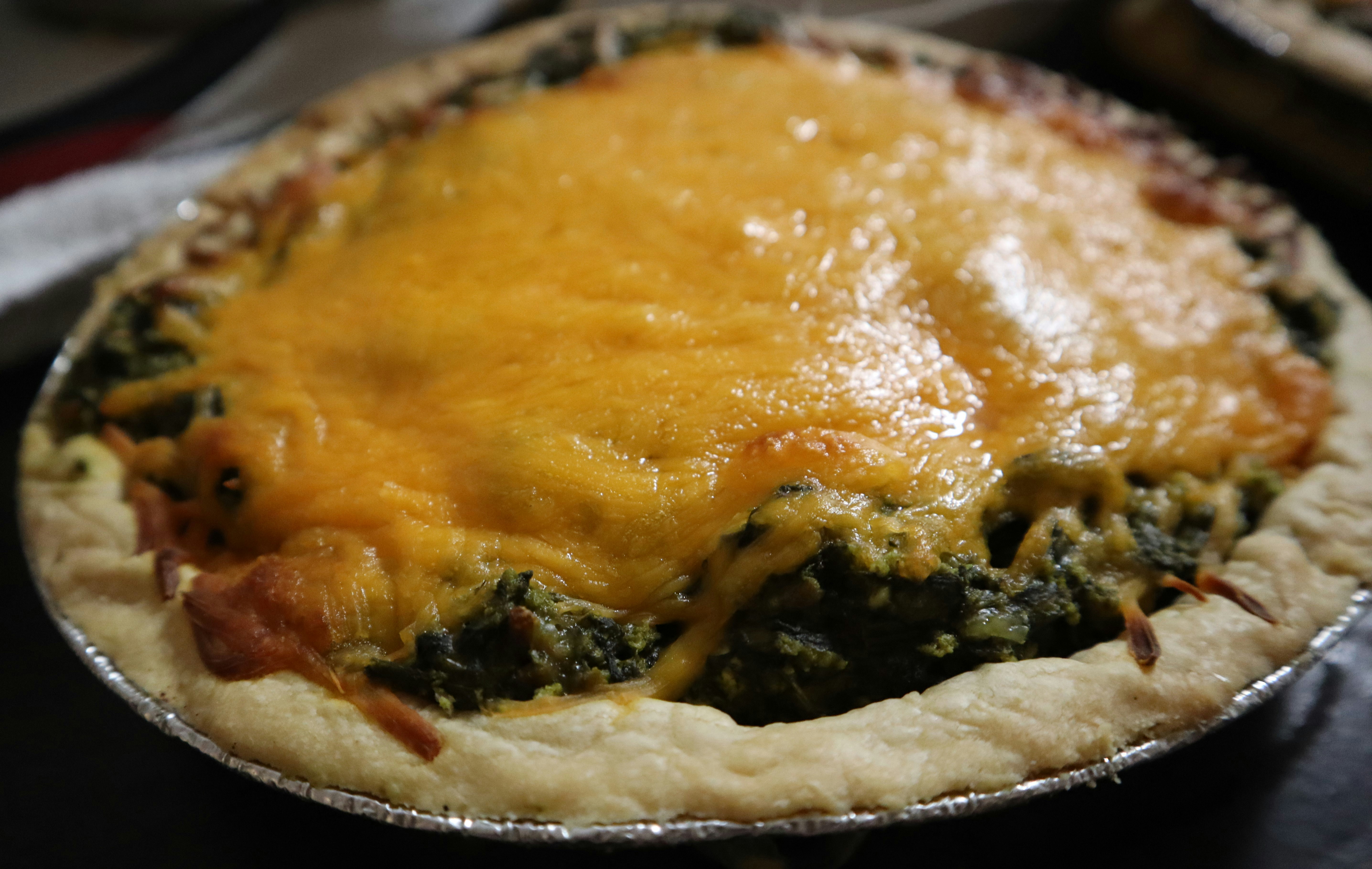 A quiche with cheese and spinach in a pie pan