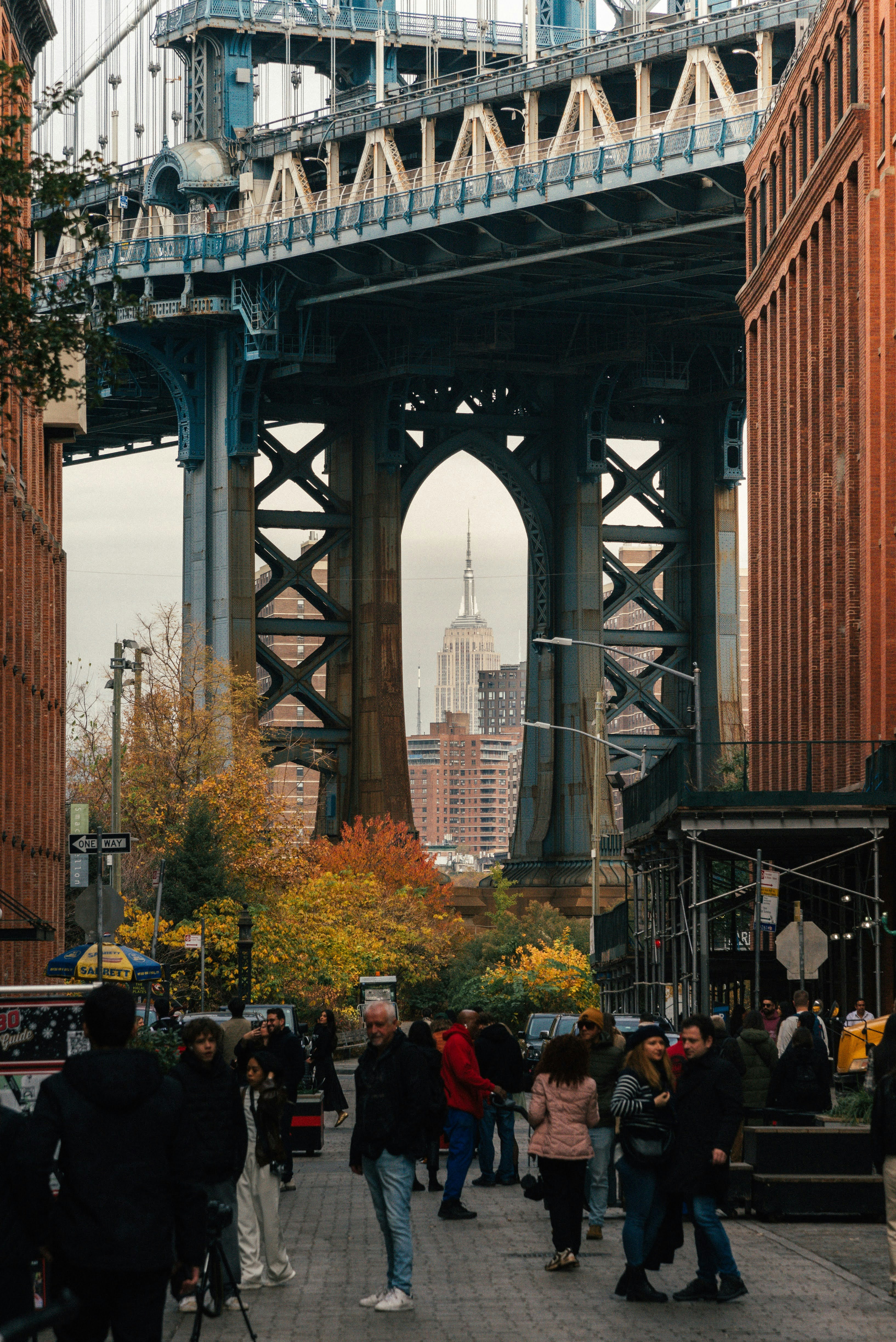 A group of people walking down a street under a bridge