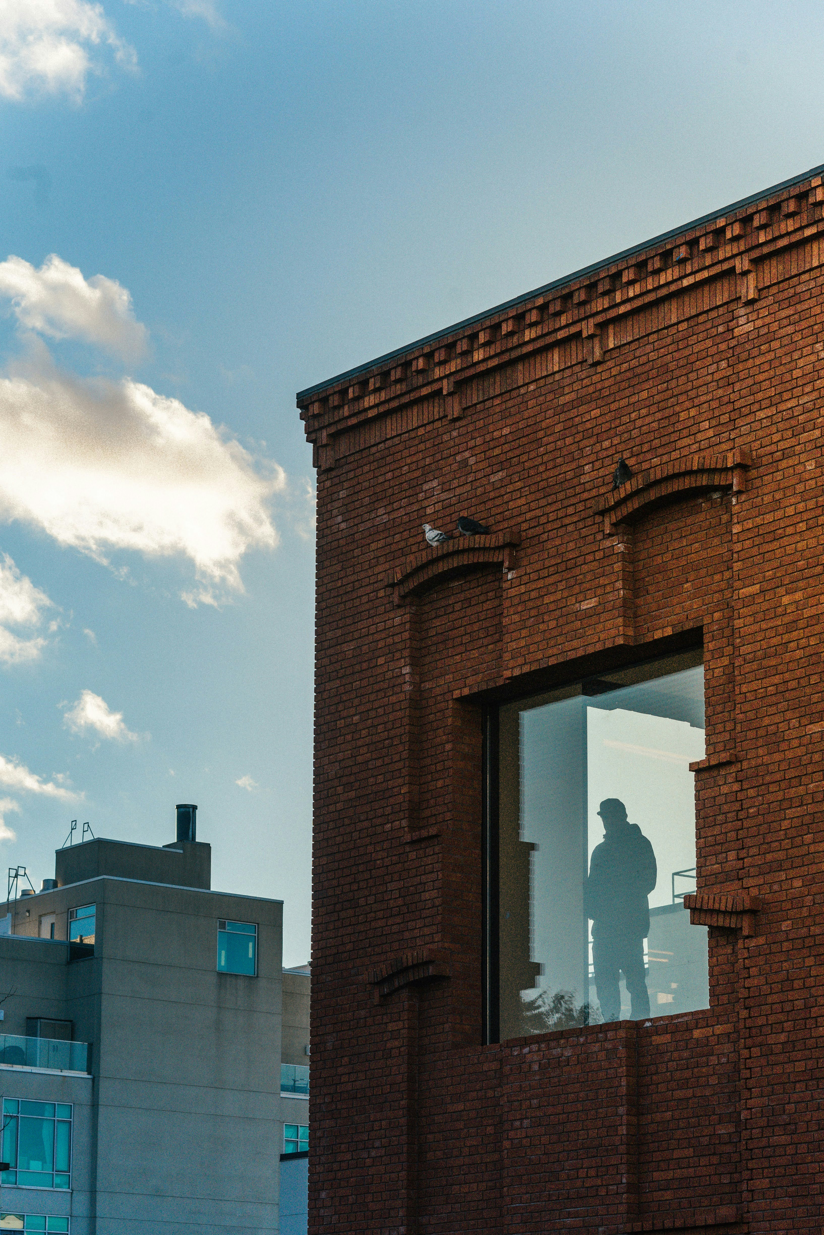 A man standing in a window of a brick building