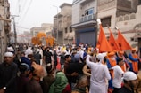 A crowd of people walking down a street holding orange flags