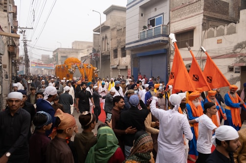 A crowd of people walking down a street holding orange flags